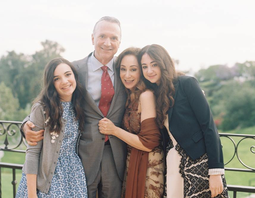 A picture showing Jessica and her two daughters in dresses. In the middle is her partner in a suit.