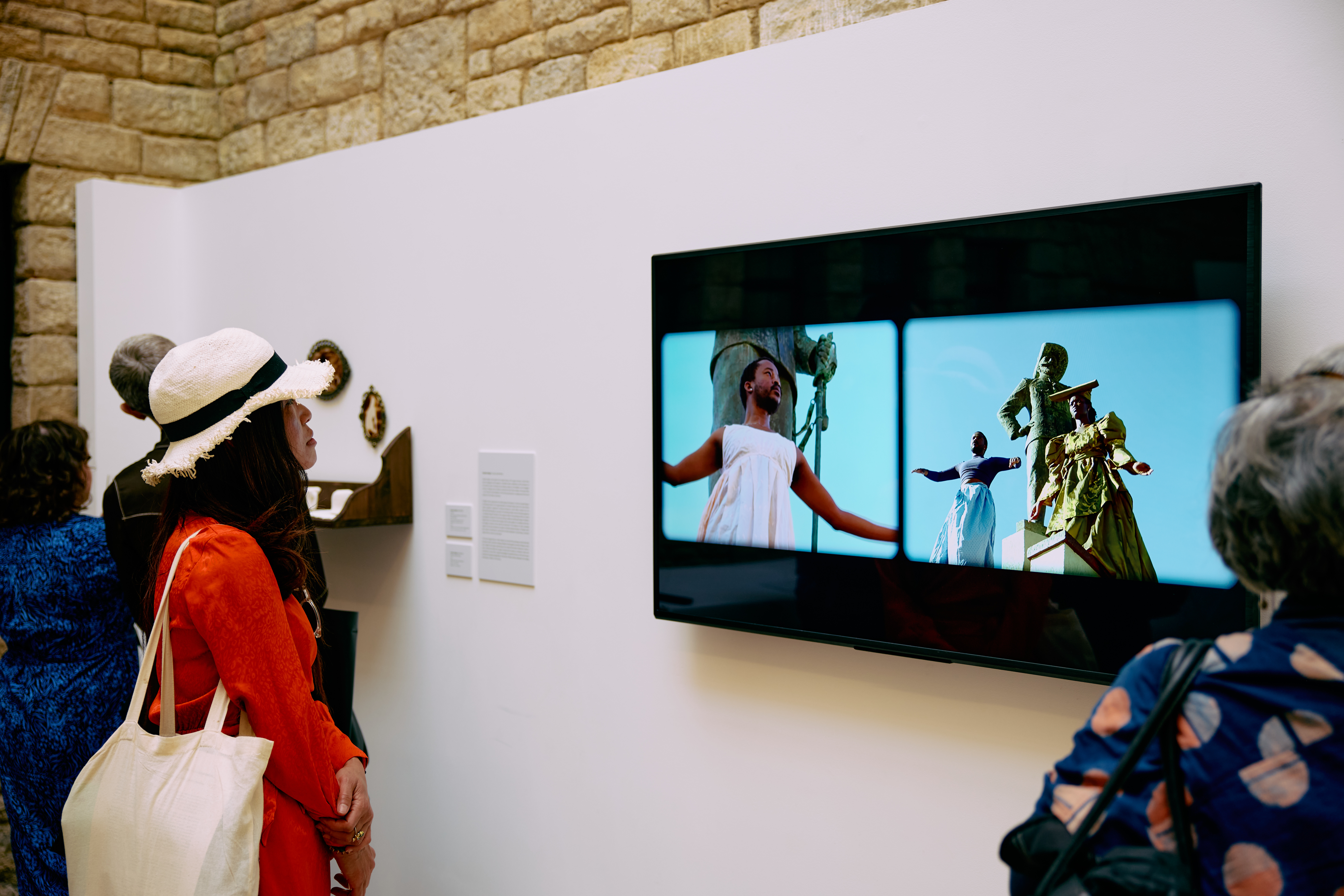 A woman watching a film titled Man of War: Leave My House by Gift Uzera, Muningandu Hoveka and Nicola Brandt