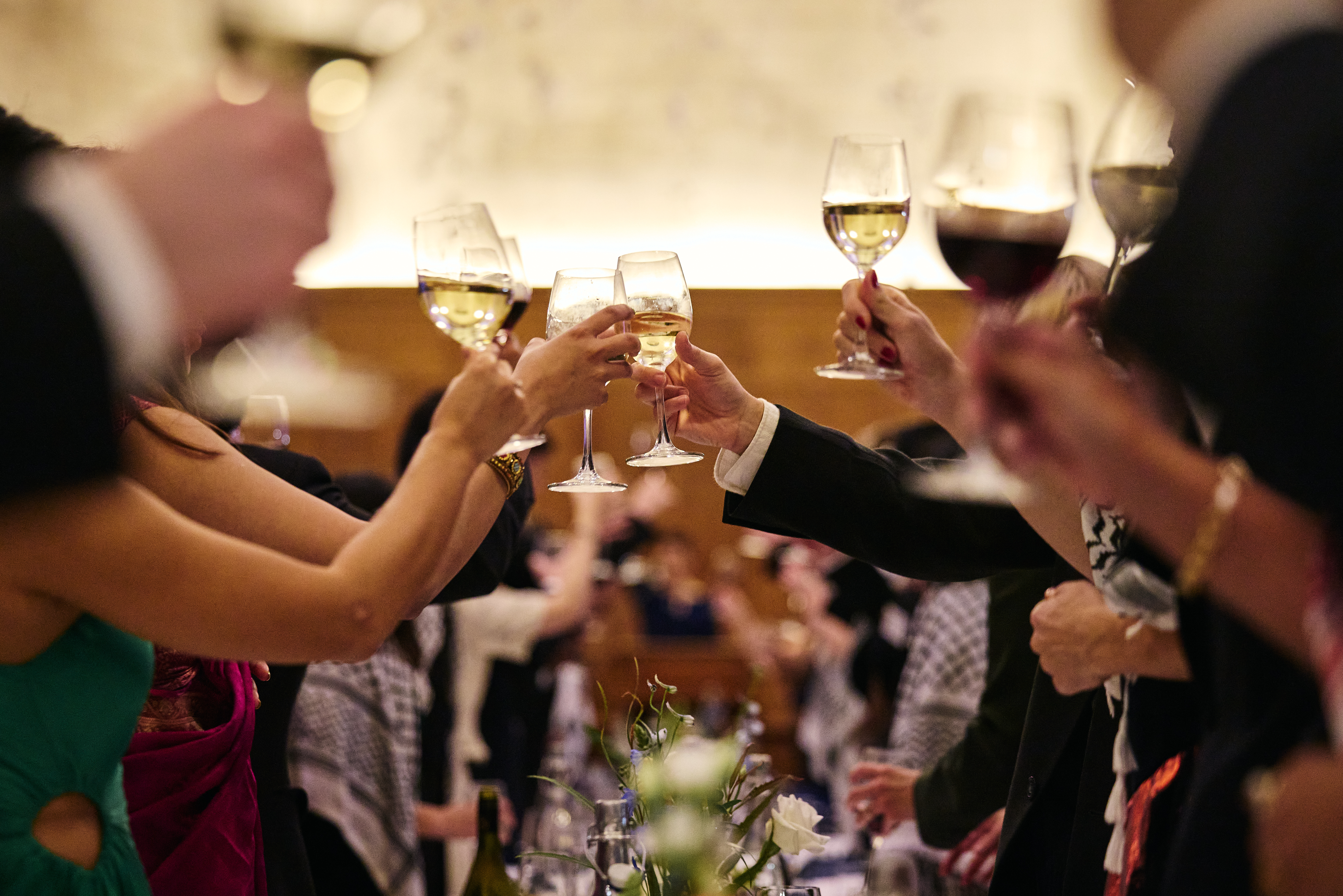 Hands raised with glasses of wine for a toast.
