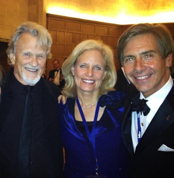 Elliot stood to the right of two friends, all in formal attire, smiling.