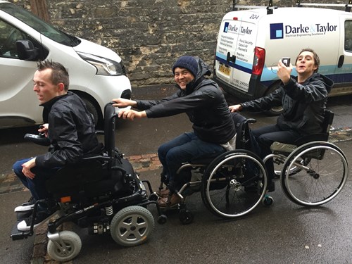 Matt, with two other people in wheelchairs, holding onto one another's wheelchairs.