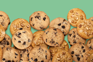 Chocolate chip cookies in front of a light green background.
