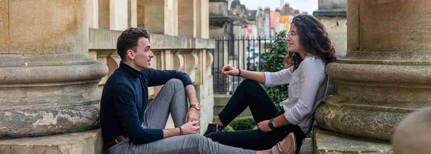 Two Rhodes Scholars sat down on a pillar talking outside the History of Science Museum in central Oxford.
