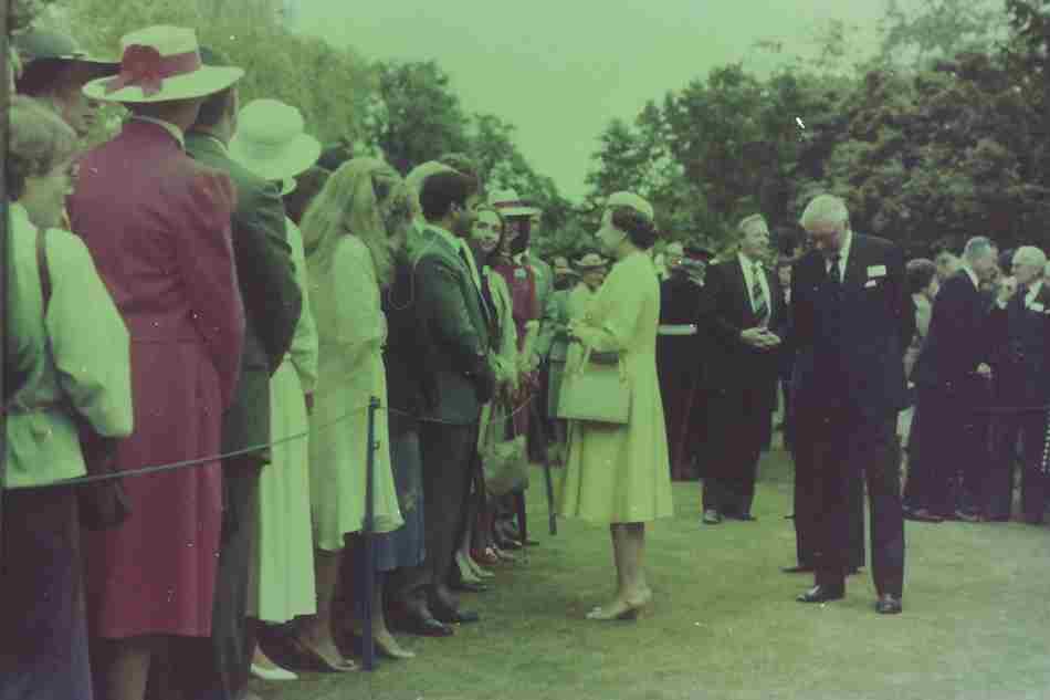 Afzal Mufti meets the Queen during a garden party at the 1983 reunion of Rhodes Scholars. A queue of people are waiting to greet the Queen to his right and Hilary Clinton stands to his left.