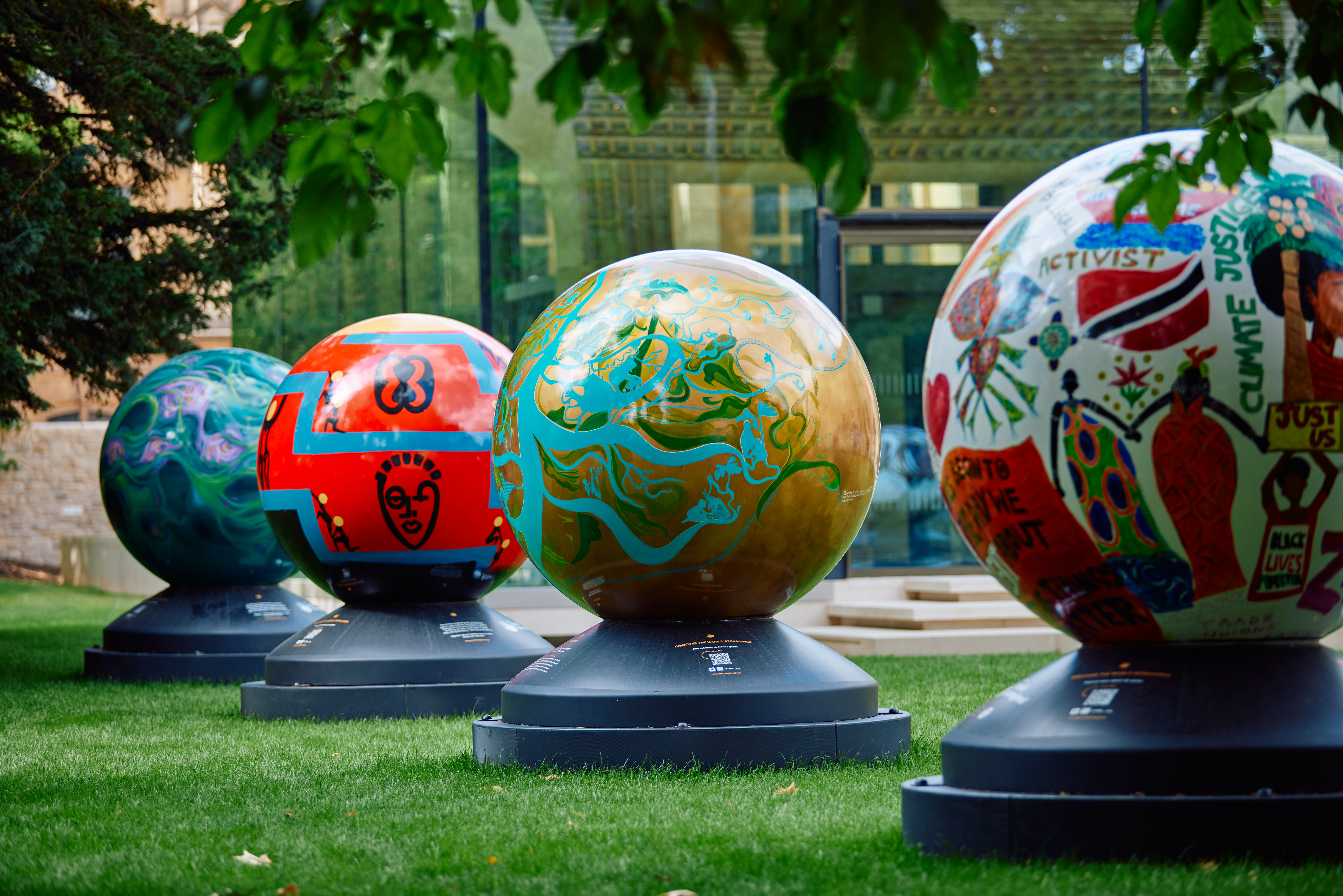 4 brightly coloured globes part of the World Reimagined exhibition in Rhodes House garden
