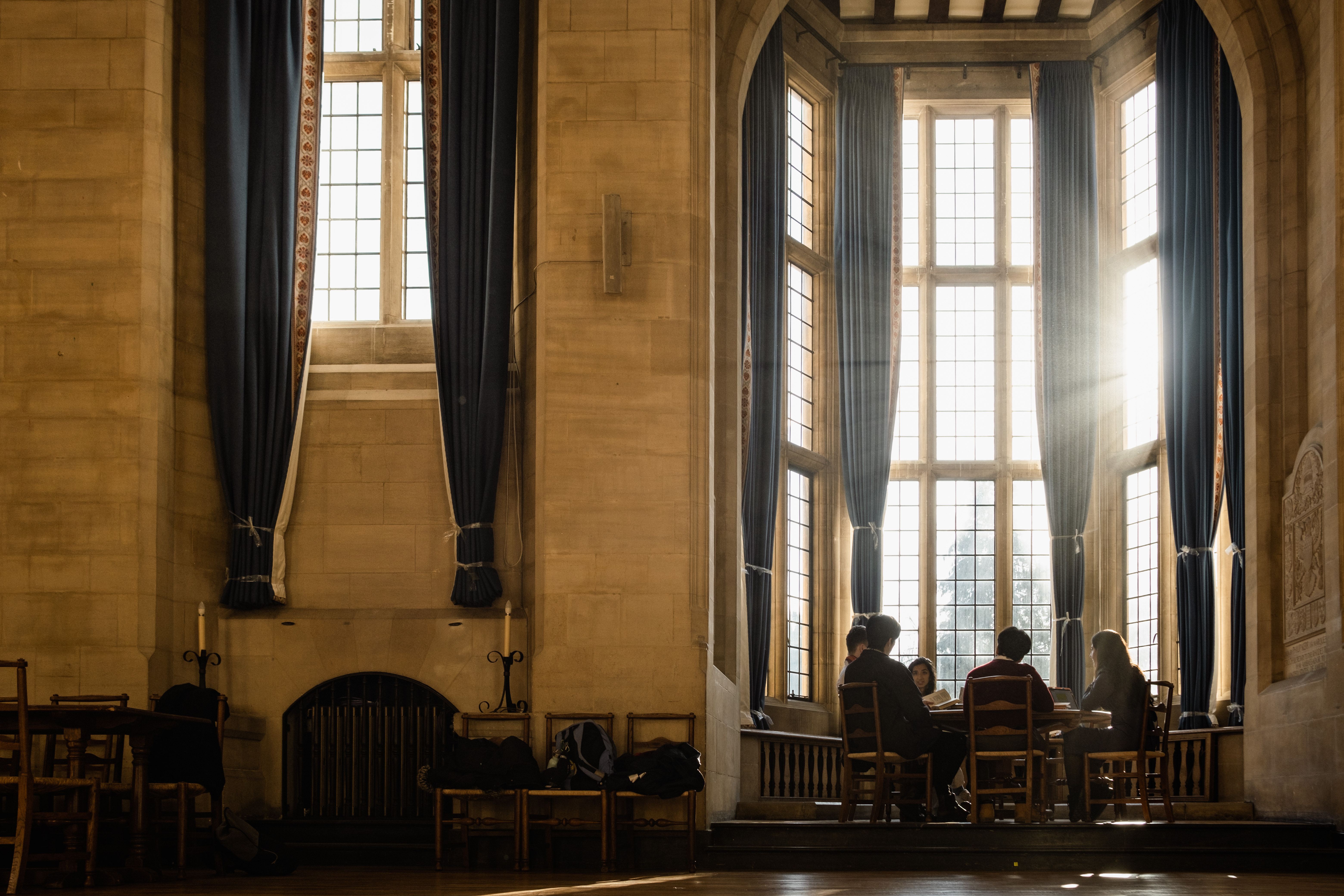 Scholars seated around a table in the bay window of Milner Hall