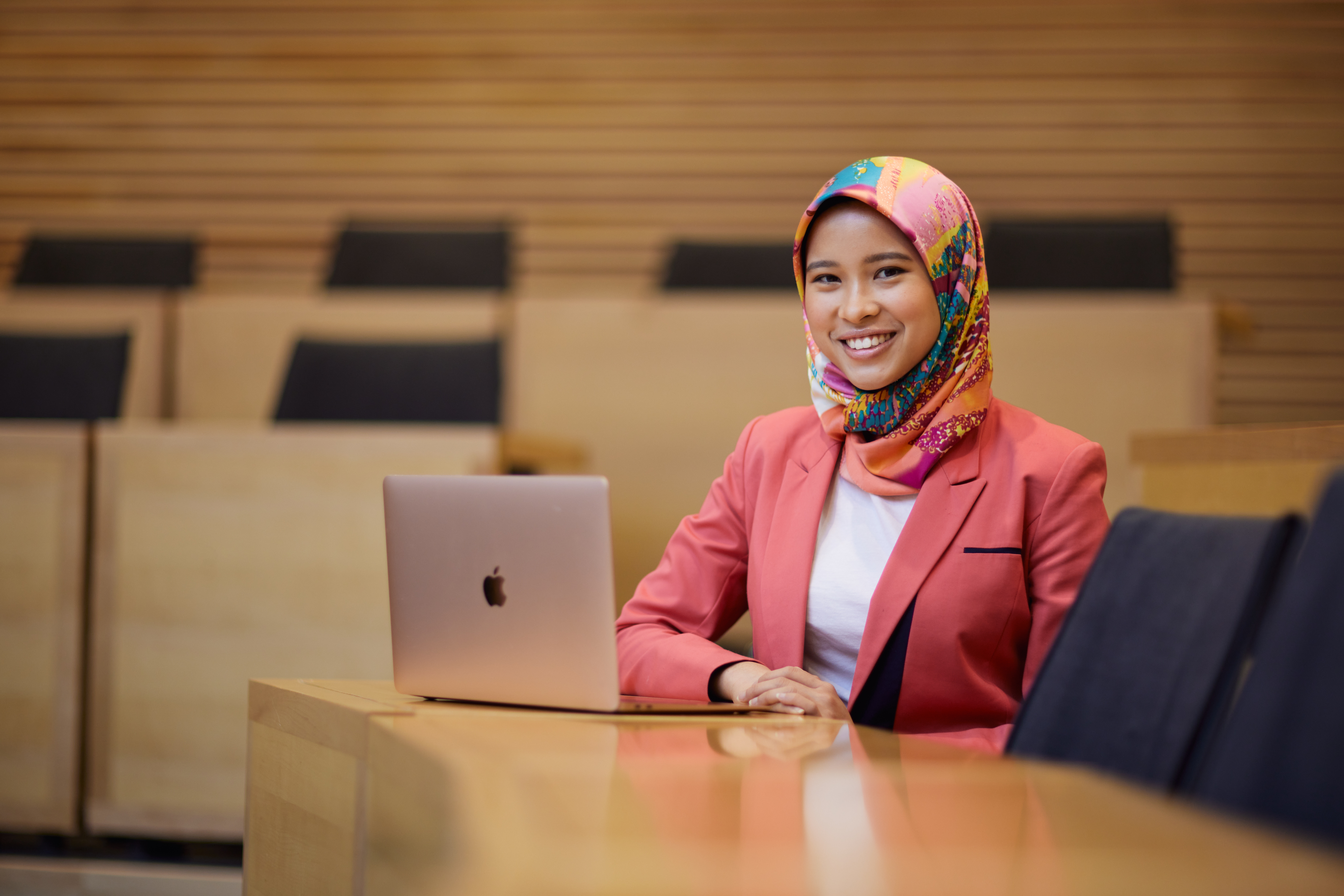 A woman sitting with a laptop in an Oxford lecture theatre