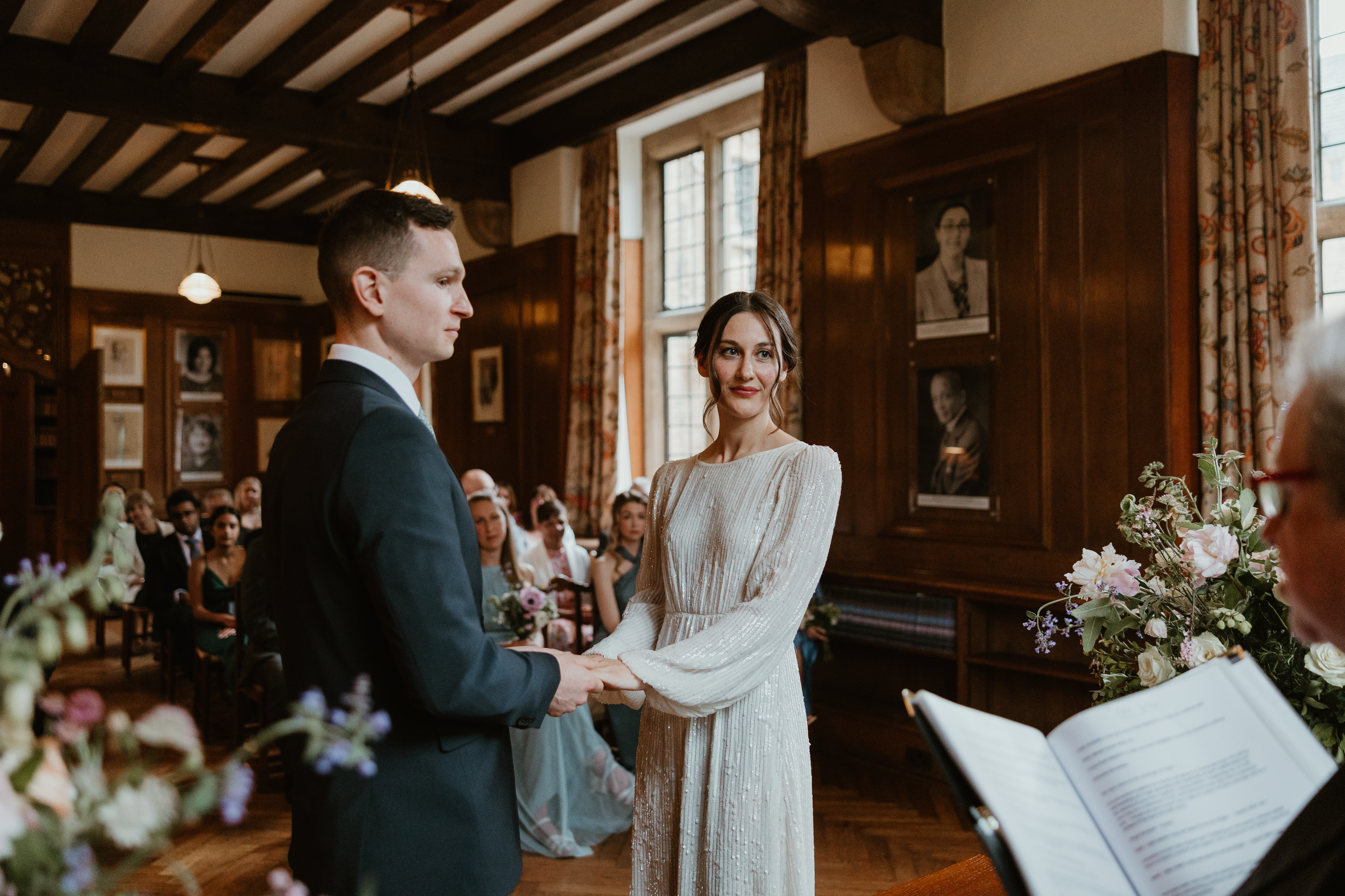 Wedding couple standing at the front of guests during ceremony in the Rhodes House Beit Room, photo courtesy of Anita Masih Photography www.anitamasih.co.uk