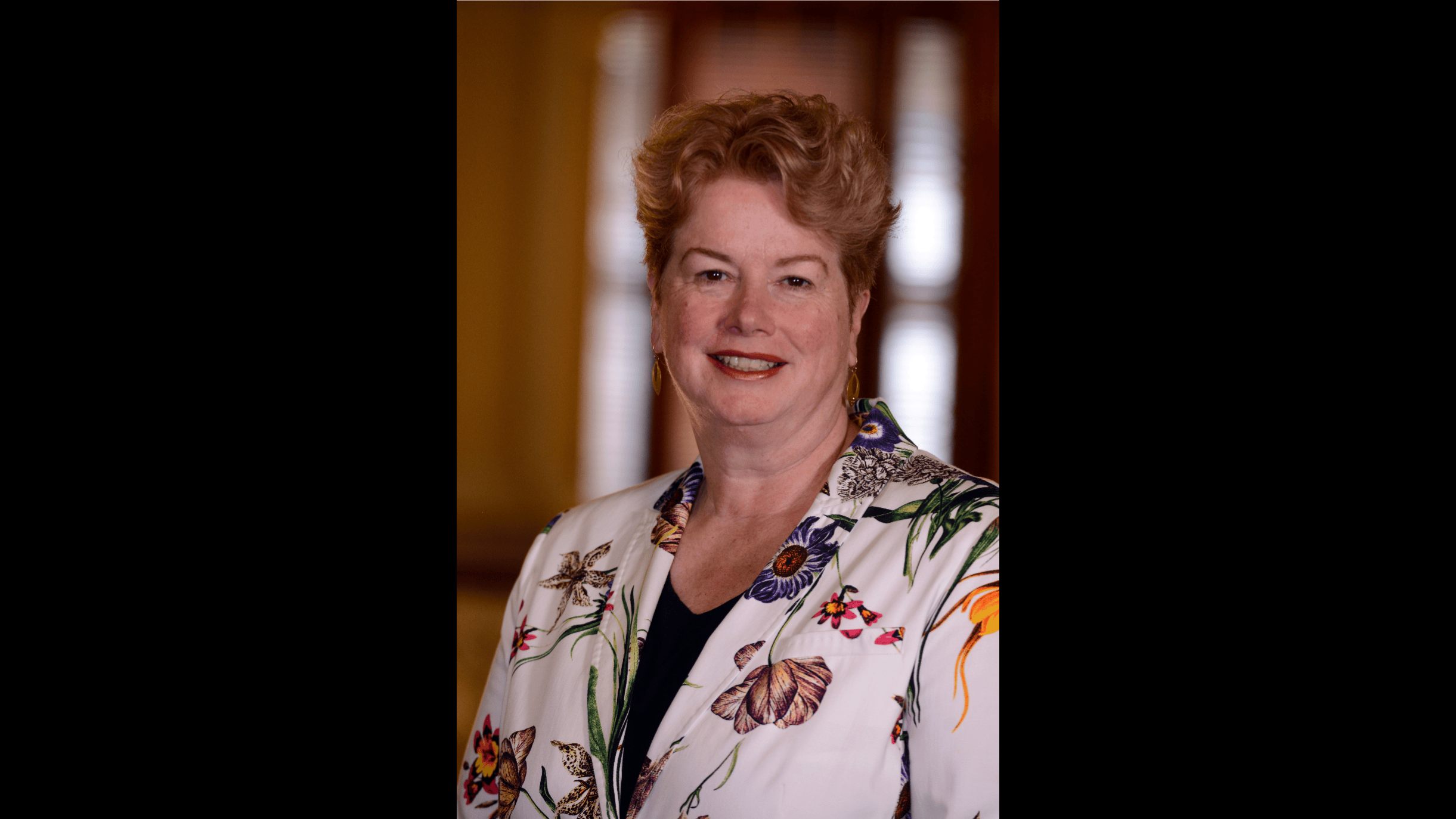 A picture of Elizabeth smiling and in a floral jacket 