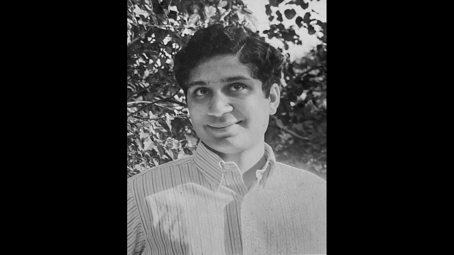 A black-and-white picture of Deepak with leaves in background