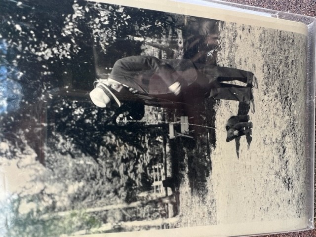 A black-and-white picture showing an old man in a suit with a baby bear at his feet. They are standing on a lawn.