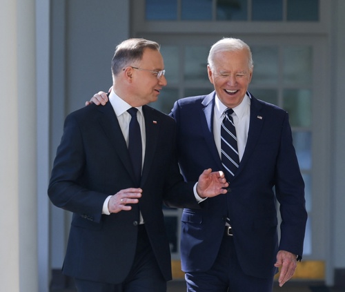 President Biden listens to President Duda speak as they walk at the White House