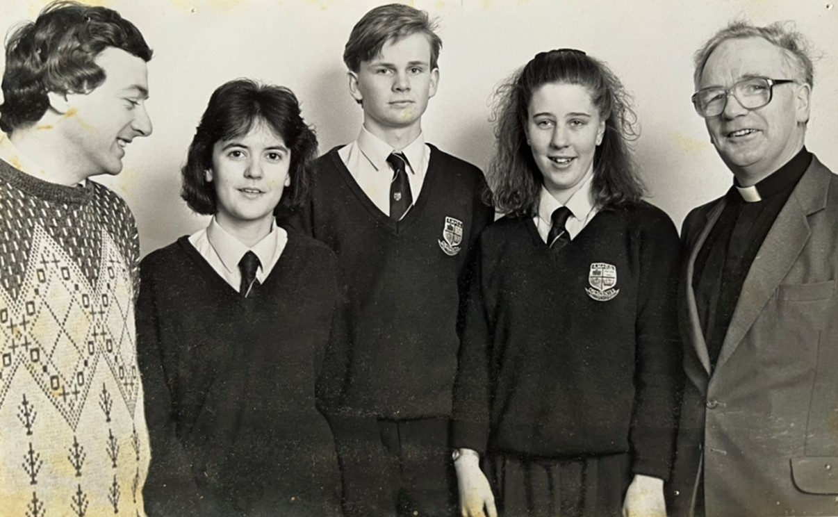 This black-and-white picture shows a group of students in uniforms with two teachers on their sides.