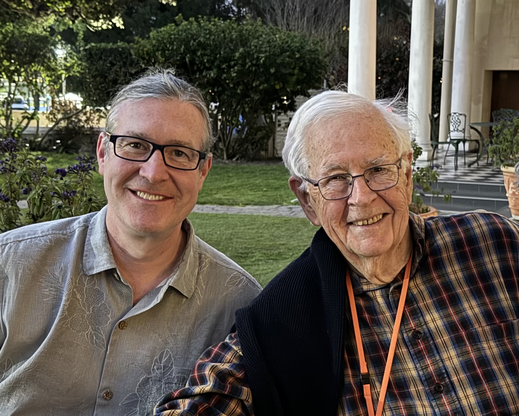 Both Norton and Dayne are sat in a garden, with Dayne to the right. They are pictured smiling.