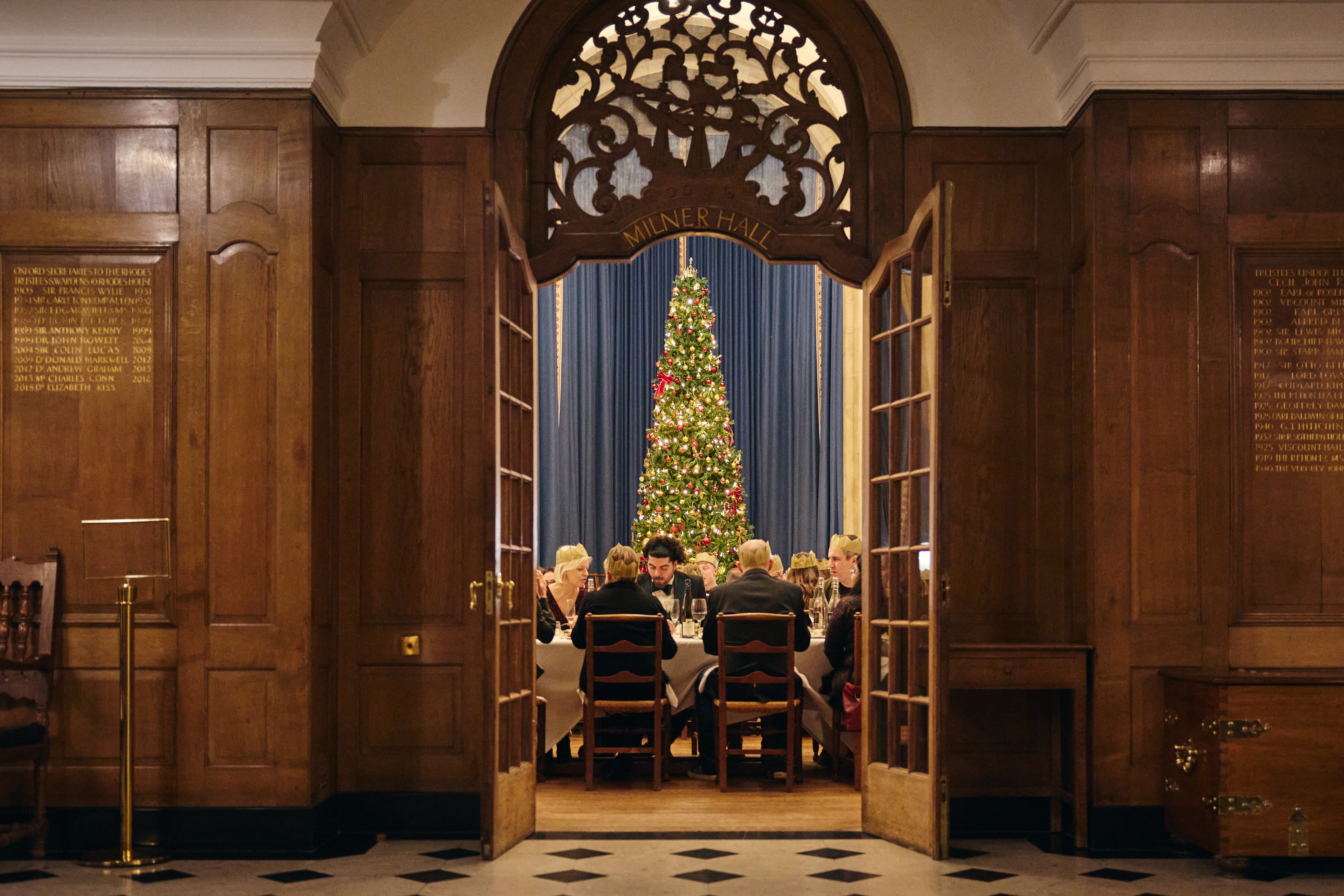 View of Rhodes House McCall MacBain Hall through the door from the vestibule, with Christmas party guests seated. 