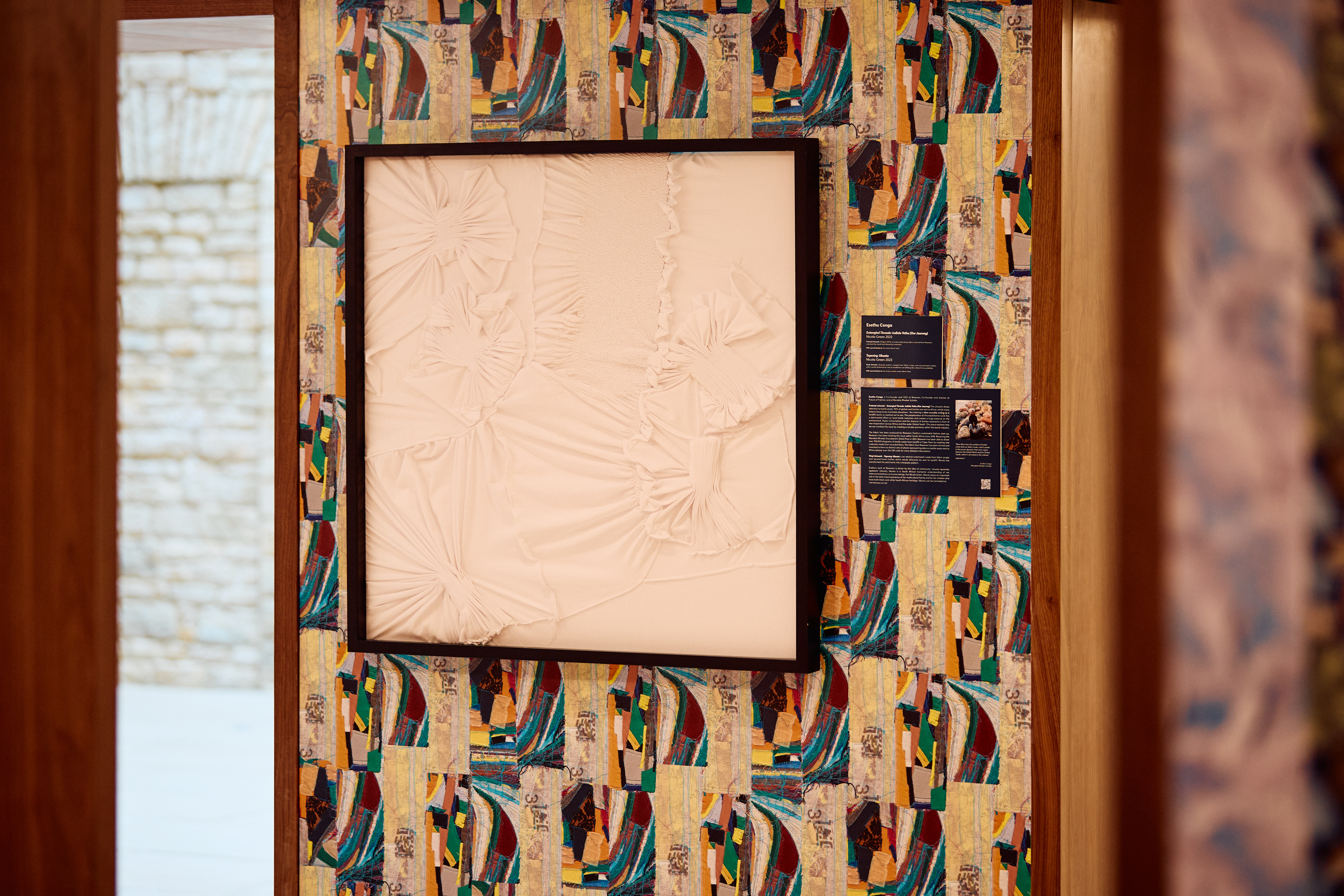 One of the artworks featuring framed white fabric against a colourful patterned wall made up of scraps of fabric