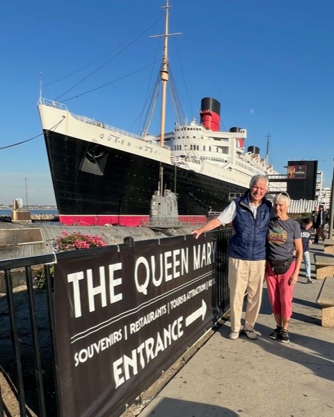 Couple stood in front of large ship.