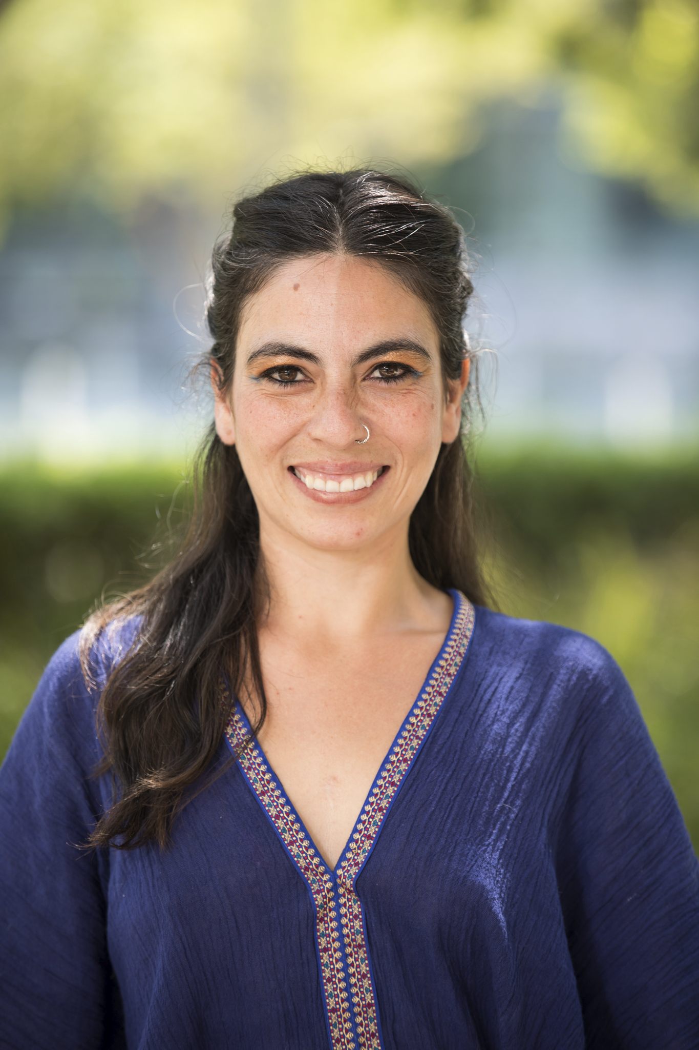 A headshot of Laura against a blurred green background
