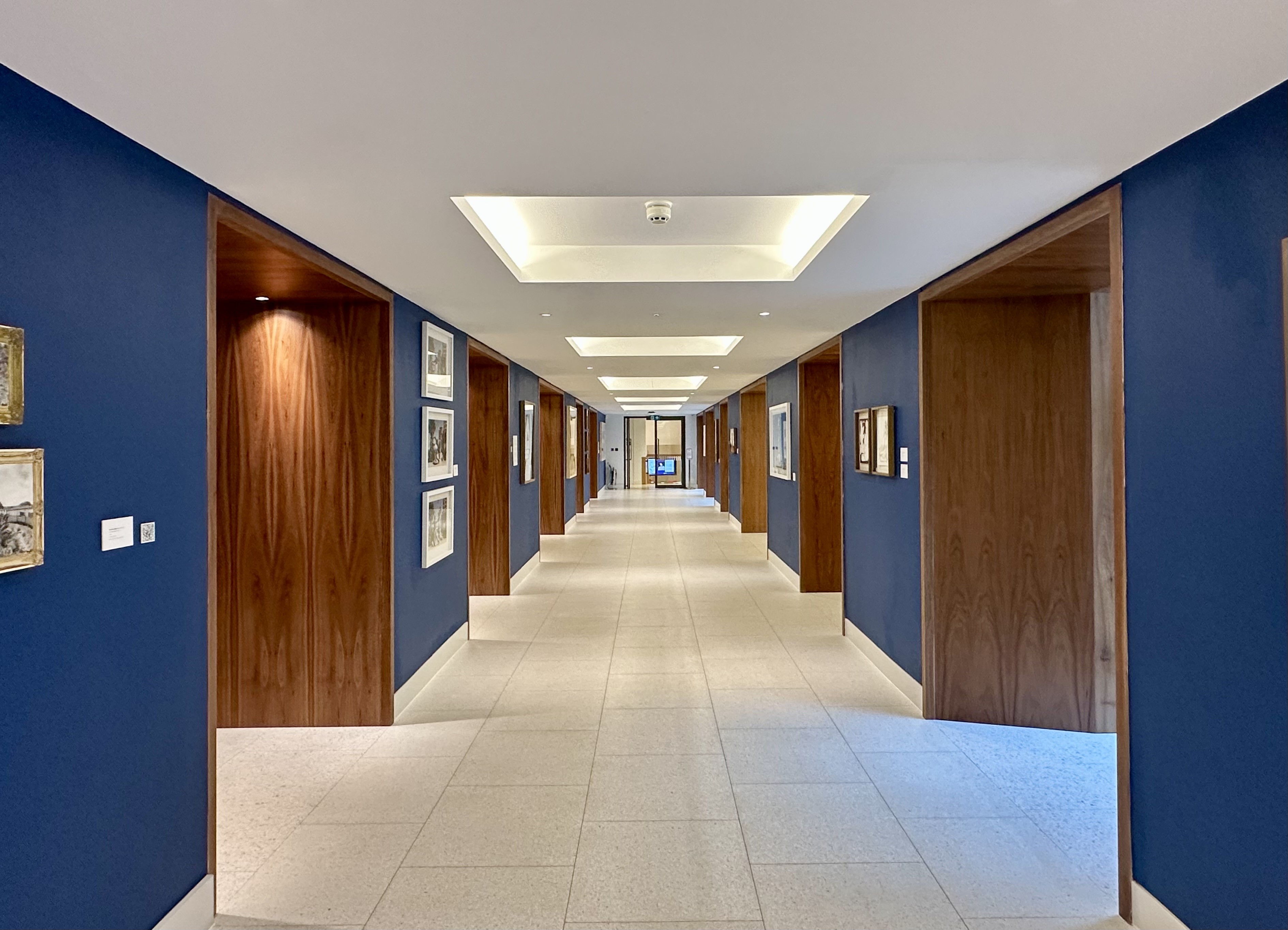 Lobby of the Rhodes House Conference Foyer with artwork hanging on the blue walls.