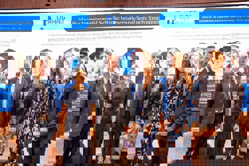 Photo shows 6 people in front of symposium backdrop