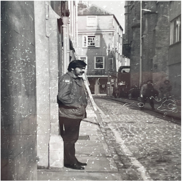 A black-and-white picture of Jahar leaning against a wall in a street in Oxford