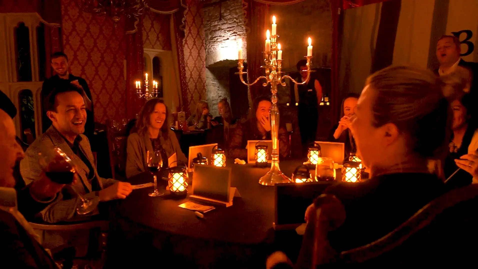 Guests gathered around a table in a darkened room playing an indoor team building game of Betrayers. 