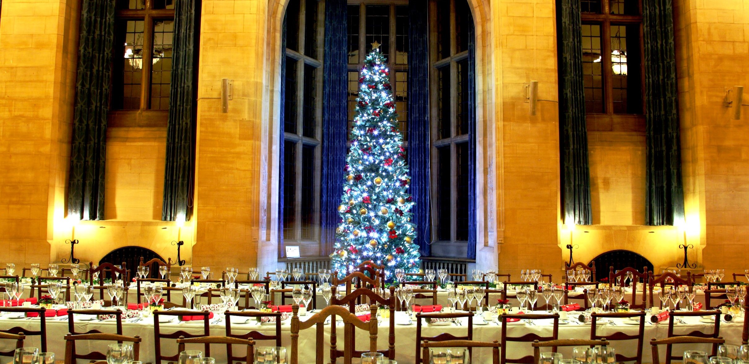Rhodes House McCall MacBain Hall set up for Christmas with a large Christmas tree in the bay window and tables laid for dinner.