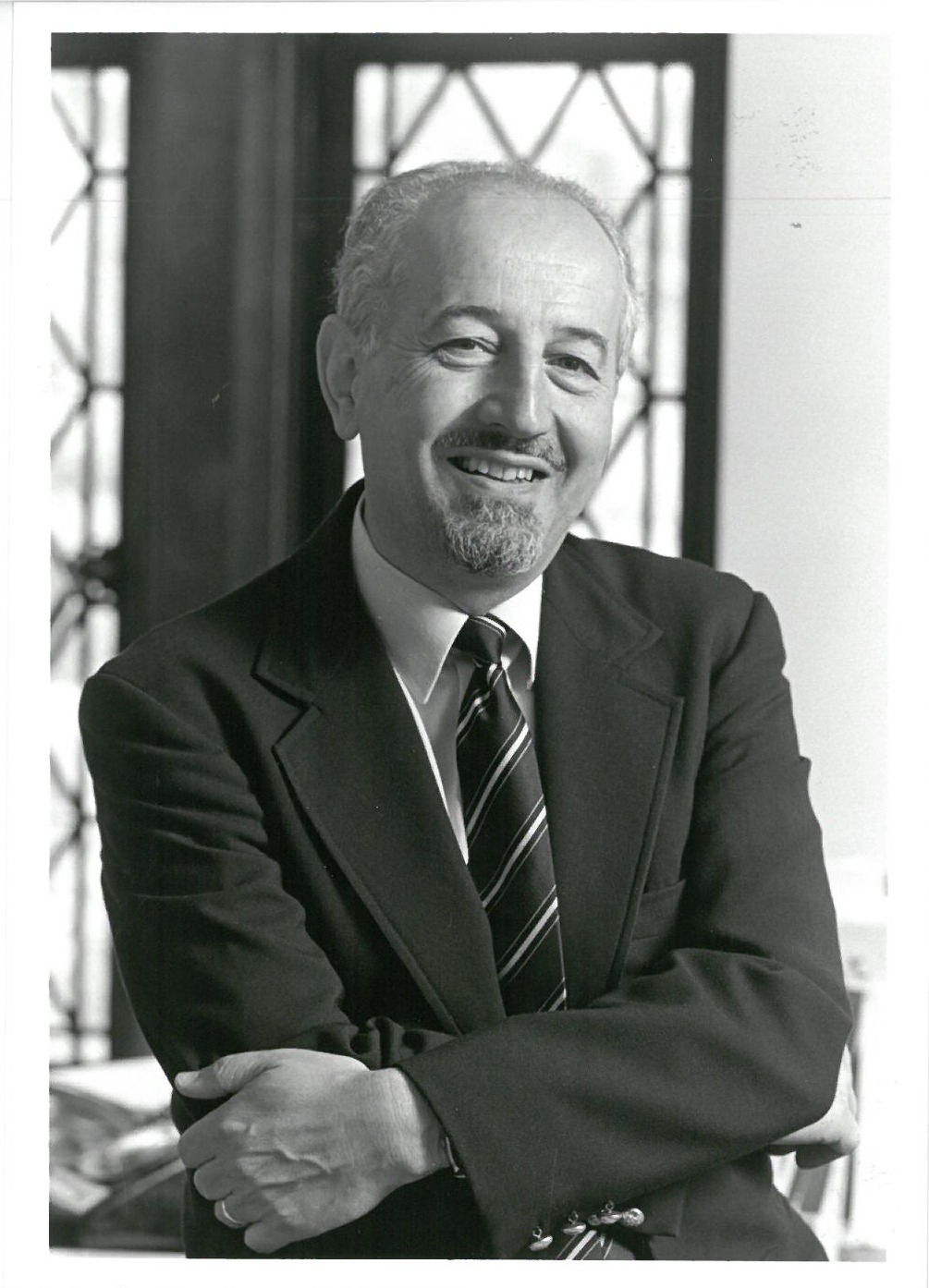 A black-and-white picture of Guido in a suit, with his arms crossed 