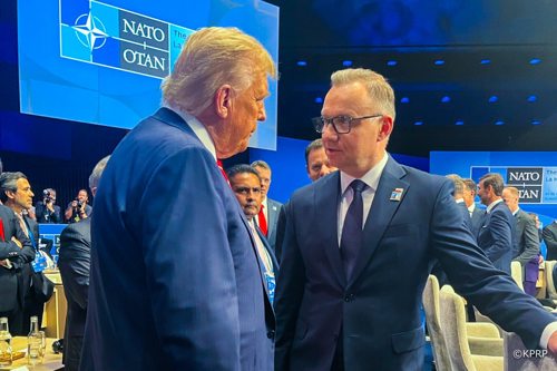 President Duda stands with his arm on a chair while talking with President Trump at a NATO conference