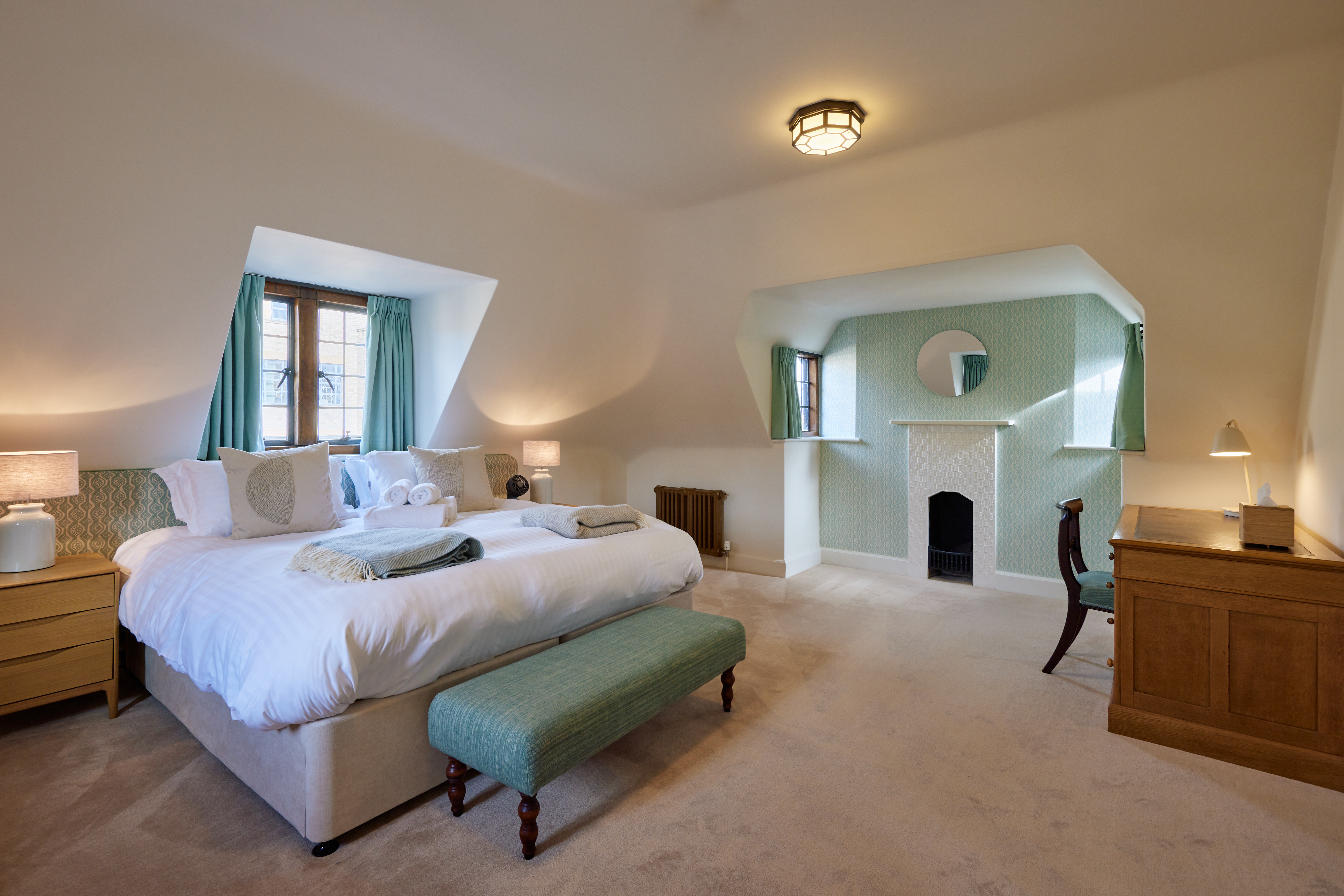 Rhodes House accommodation - A Bedroom With White Walls And Pale Green Soft Furnishings; On The Opposite Side Of The Room Facing The Camera Is A Green Painted Fireplace
