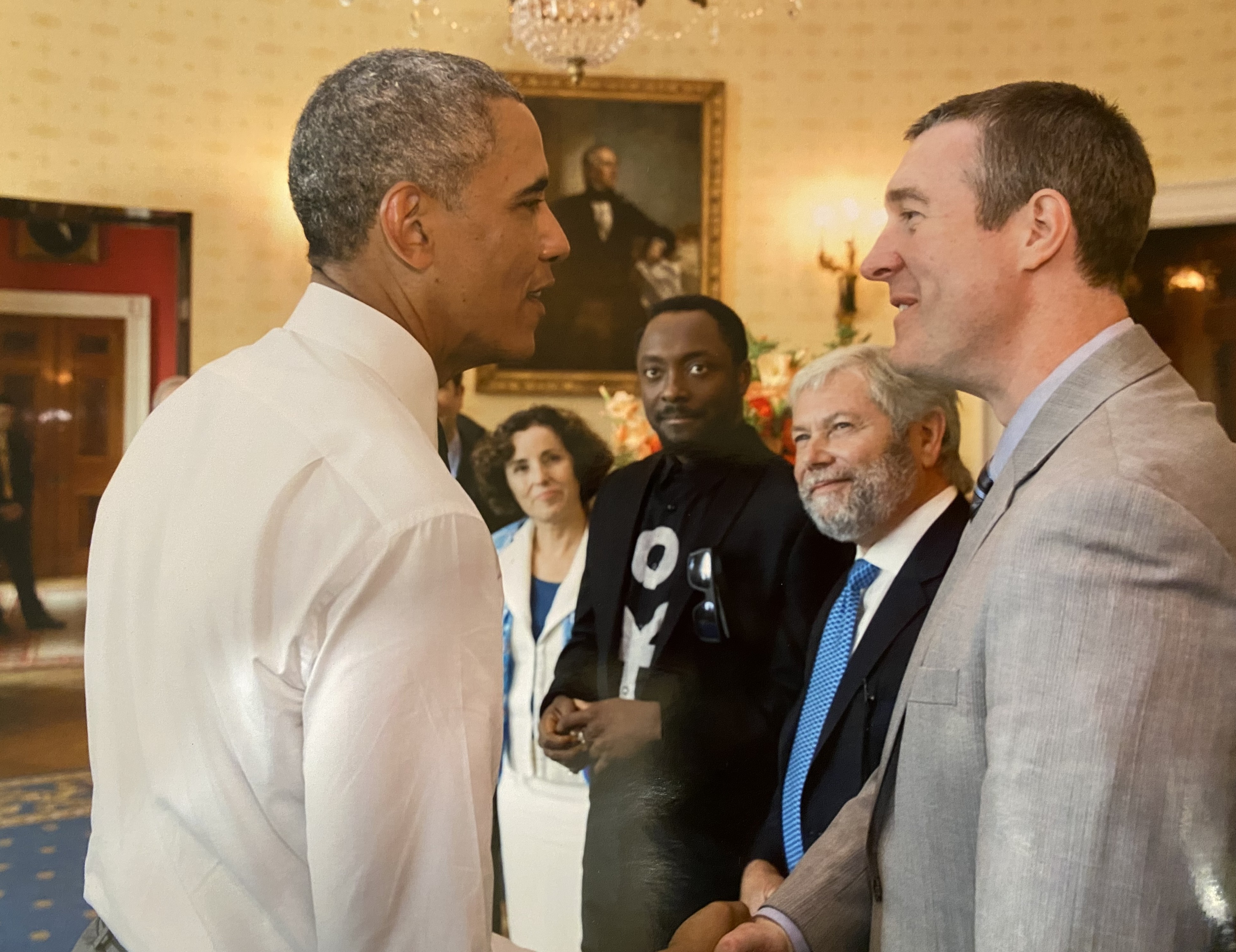 Dayne pictured shaking hands with Barak Obama, both smiling at each other. There is 3 other people in the frame, all expectantly looking at Obama.