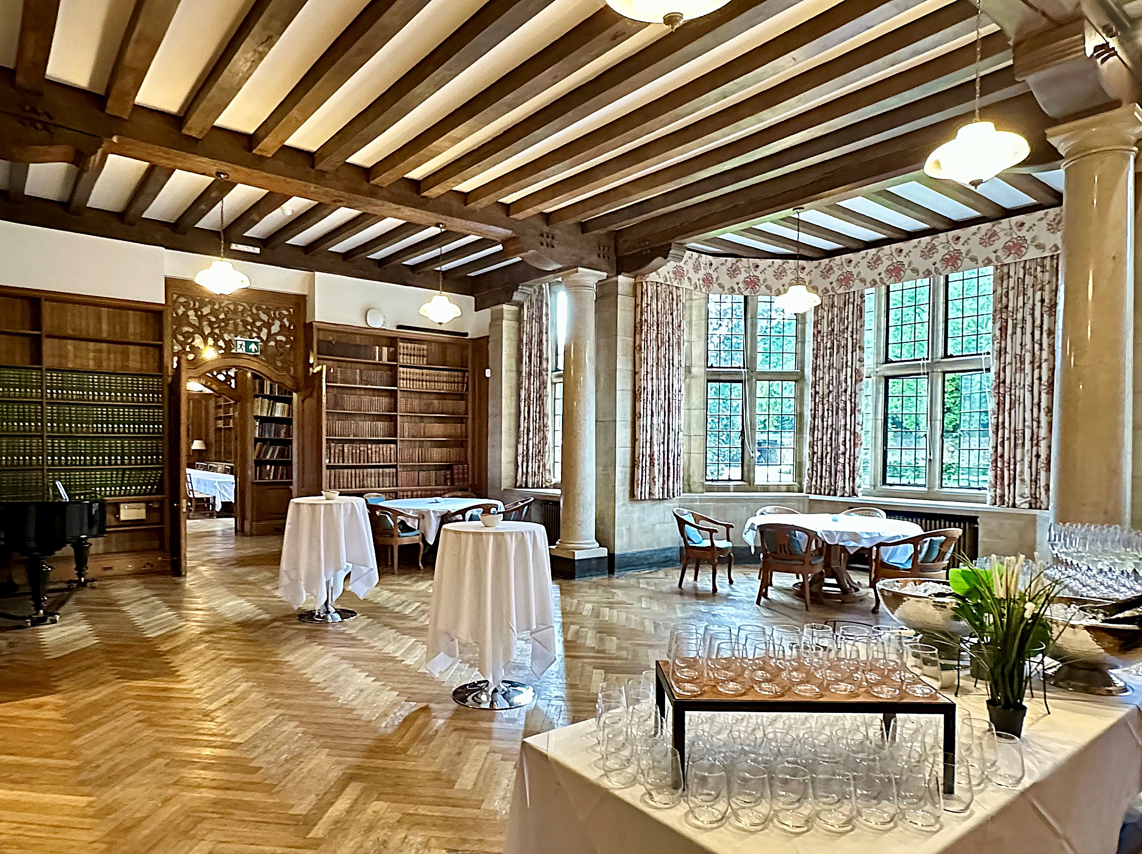 Rhodes House Reception Room set up for a drinks reception with two clothed poseur tables and a table with glasses in the foreground.