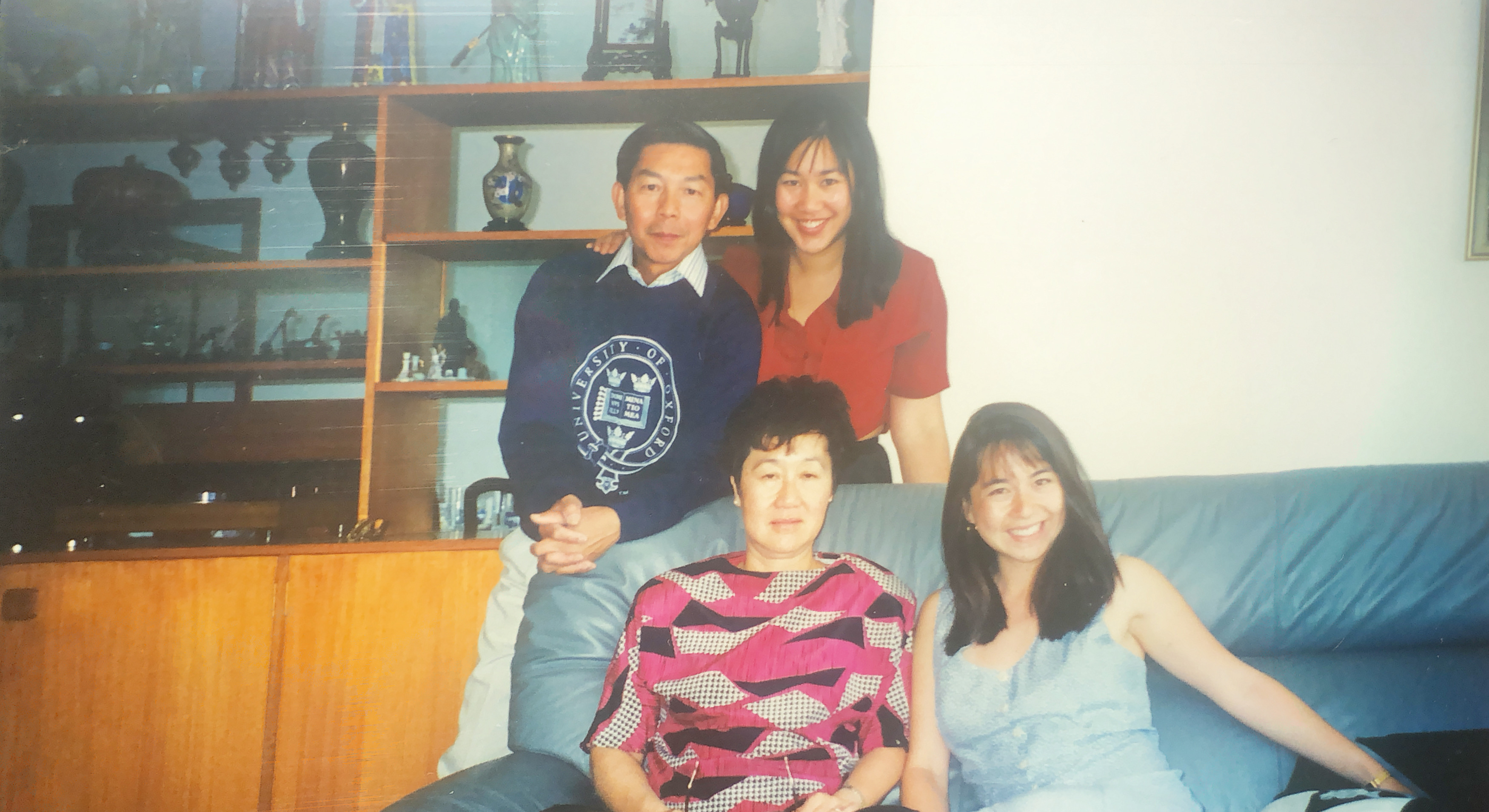 Photograph of Karen and her family. Karen and her mother are sat on a blue sofa, and above them her father and sister are stood.