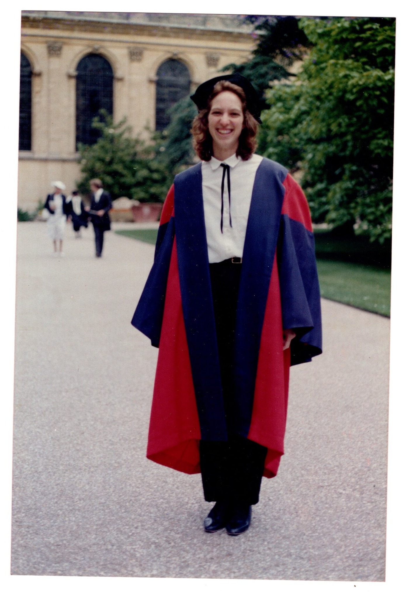 The picture shows Joy in a graduation gown with Trinity College in the background 