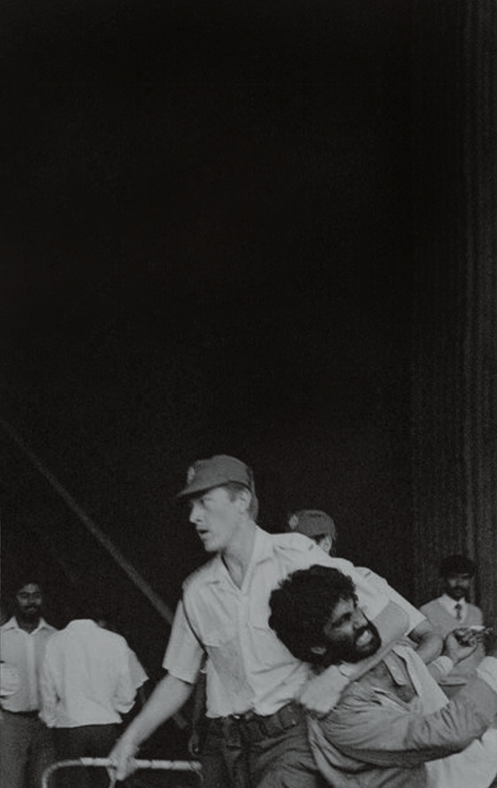 A black-and-white picture showing a policeman dragging Kumi by his neck