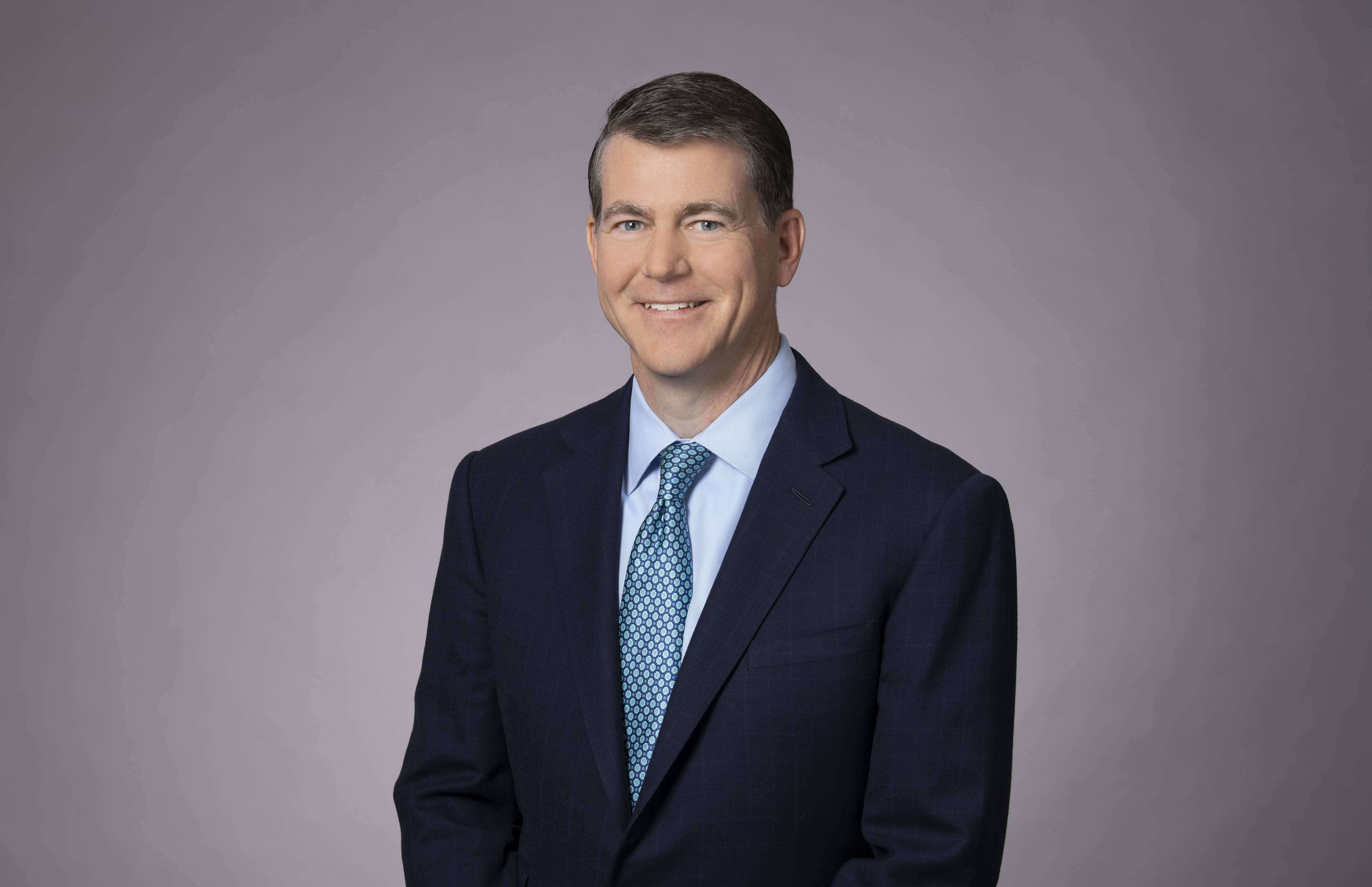 David in a suit stood smiling into the camera for a professional image.
