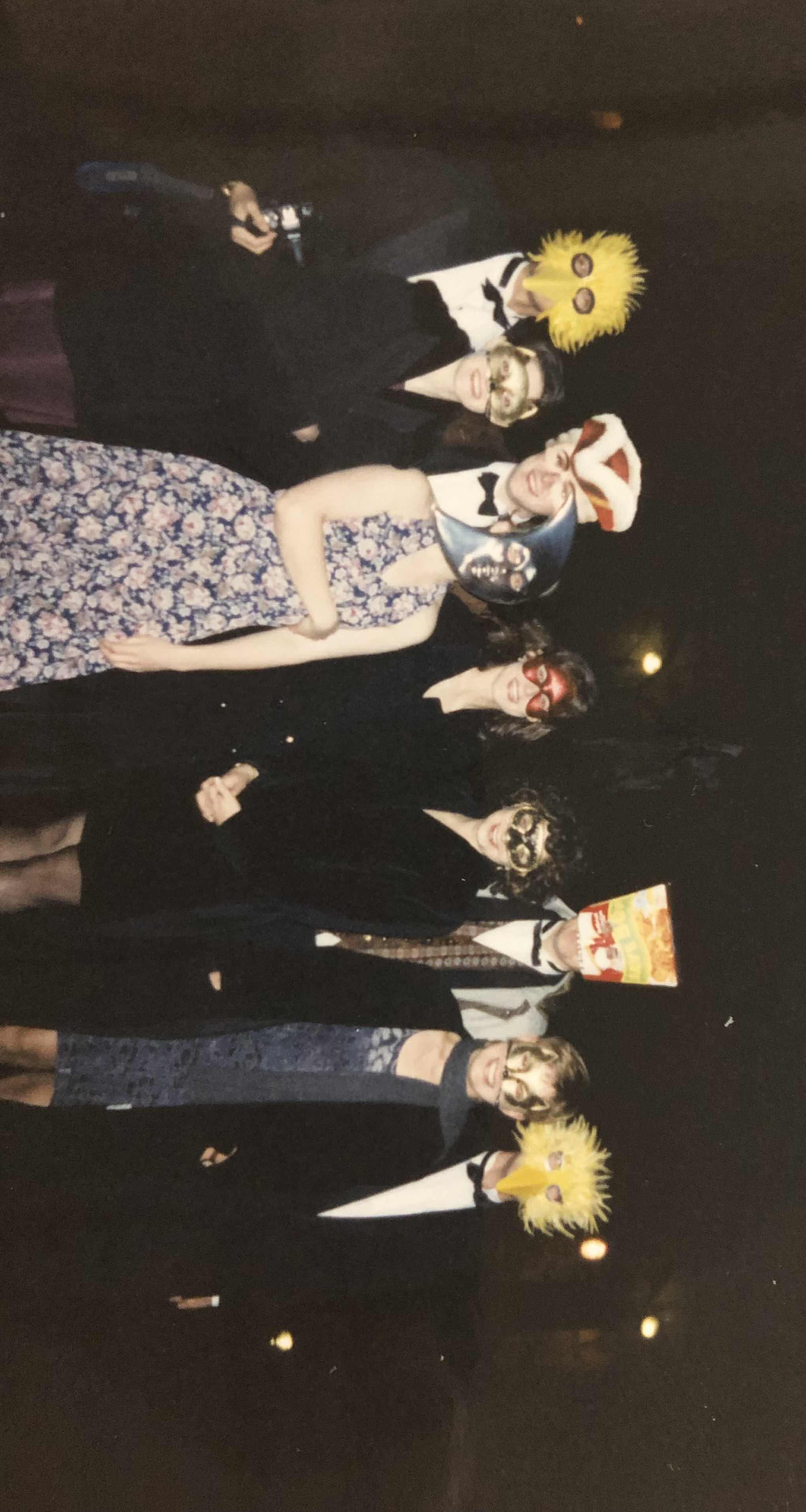 A picture showing young students in dresses and suits, with masks on their faces. Elle has a cat mask on.