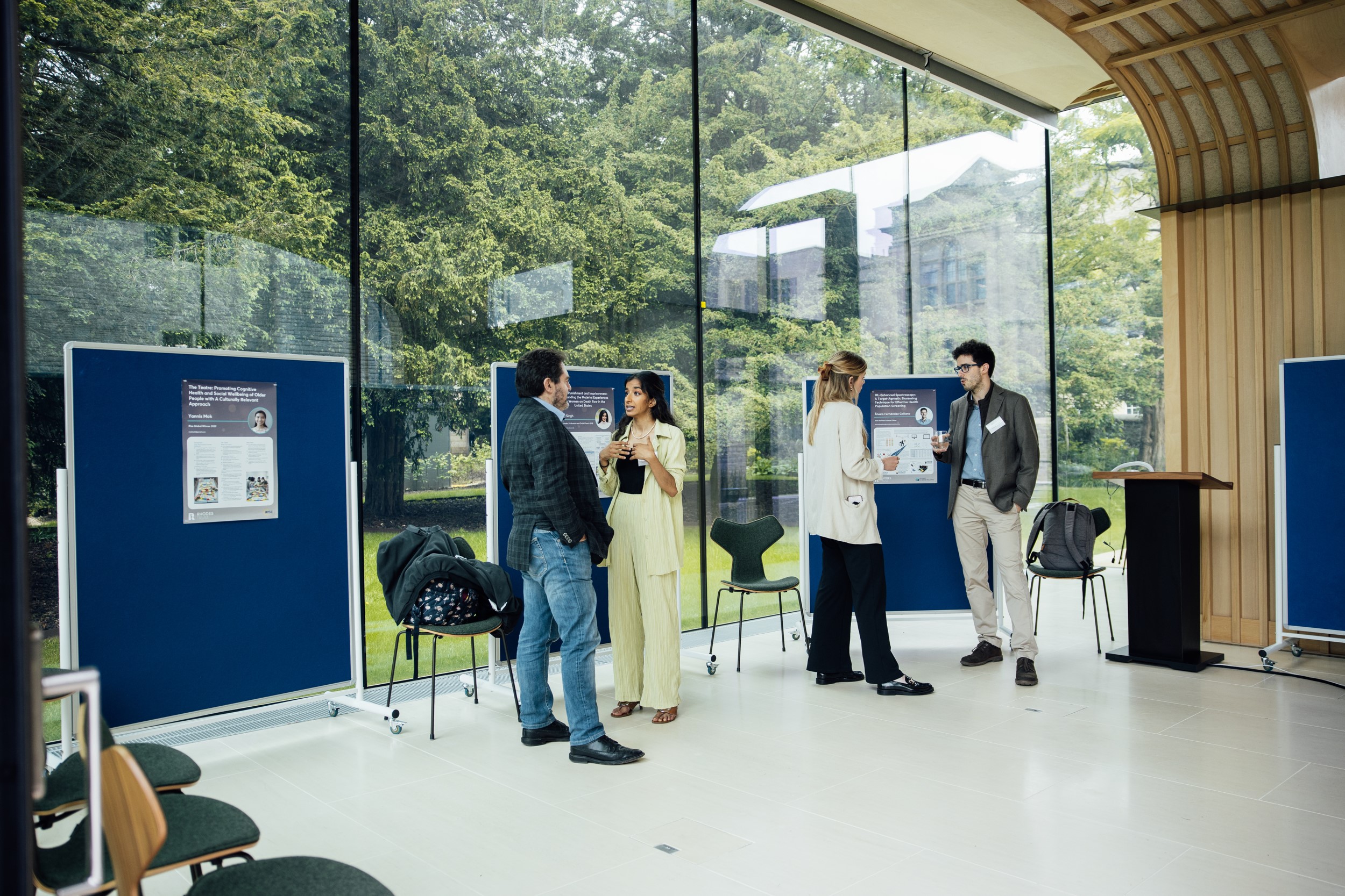 Guests attending a conference in the Rhodes House Glass Pavilion with exhibits on display boards.