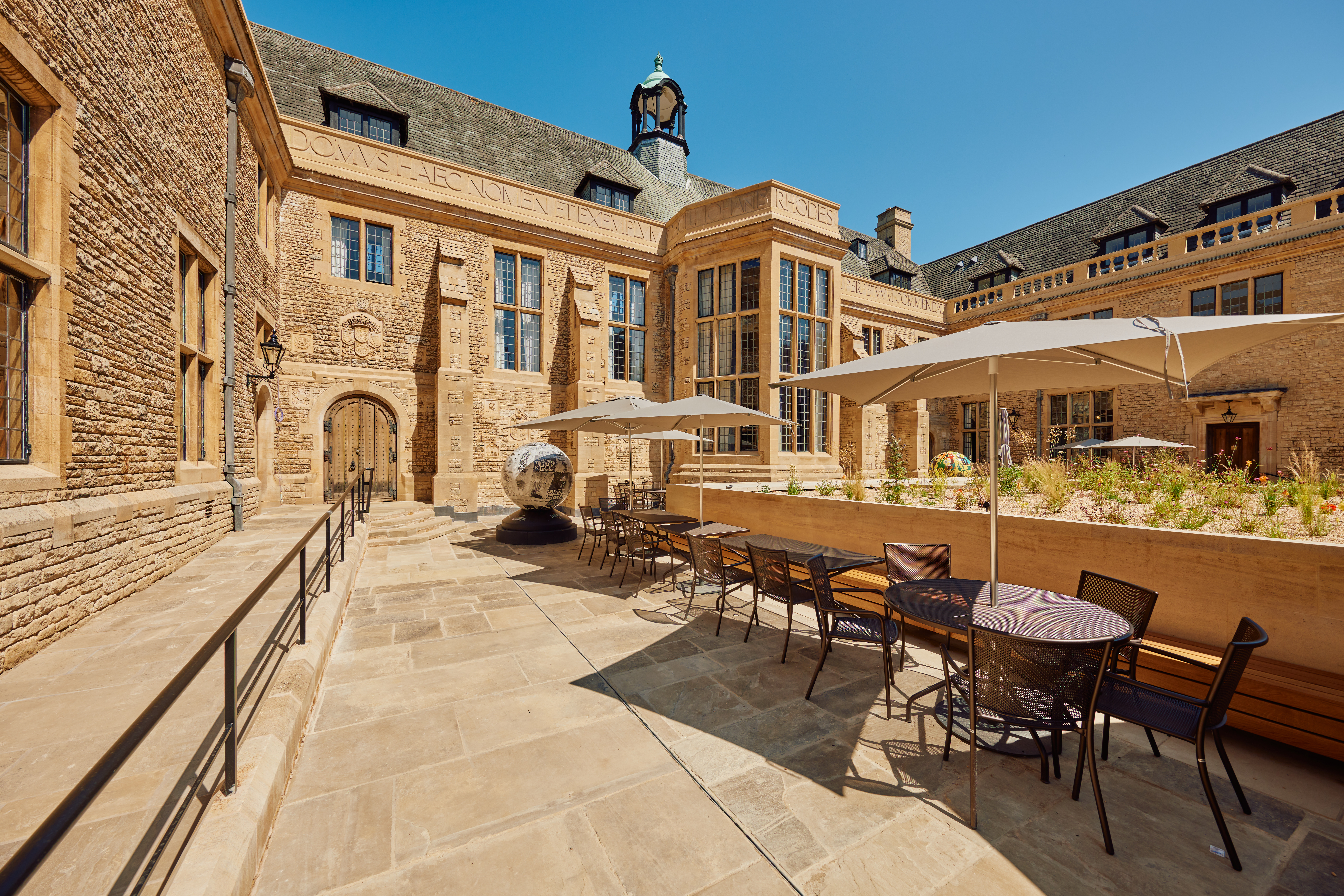 Tables and sunshades set out in the Rhodes House courtyard for meeting guests.