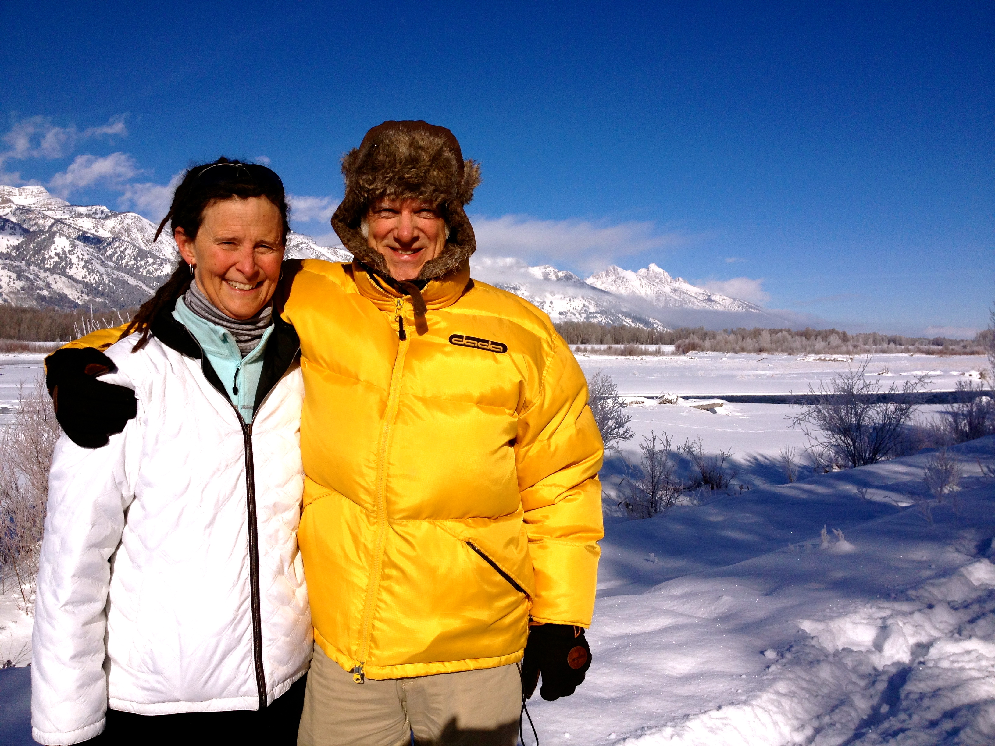 The picture shows Peter in a yellow puffer jacket with his arm around Elizabeth who is wearing a white jacket. Snowy environs around them.