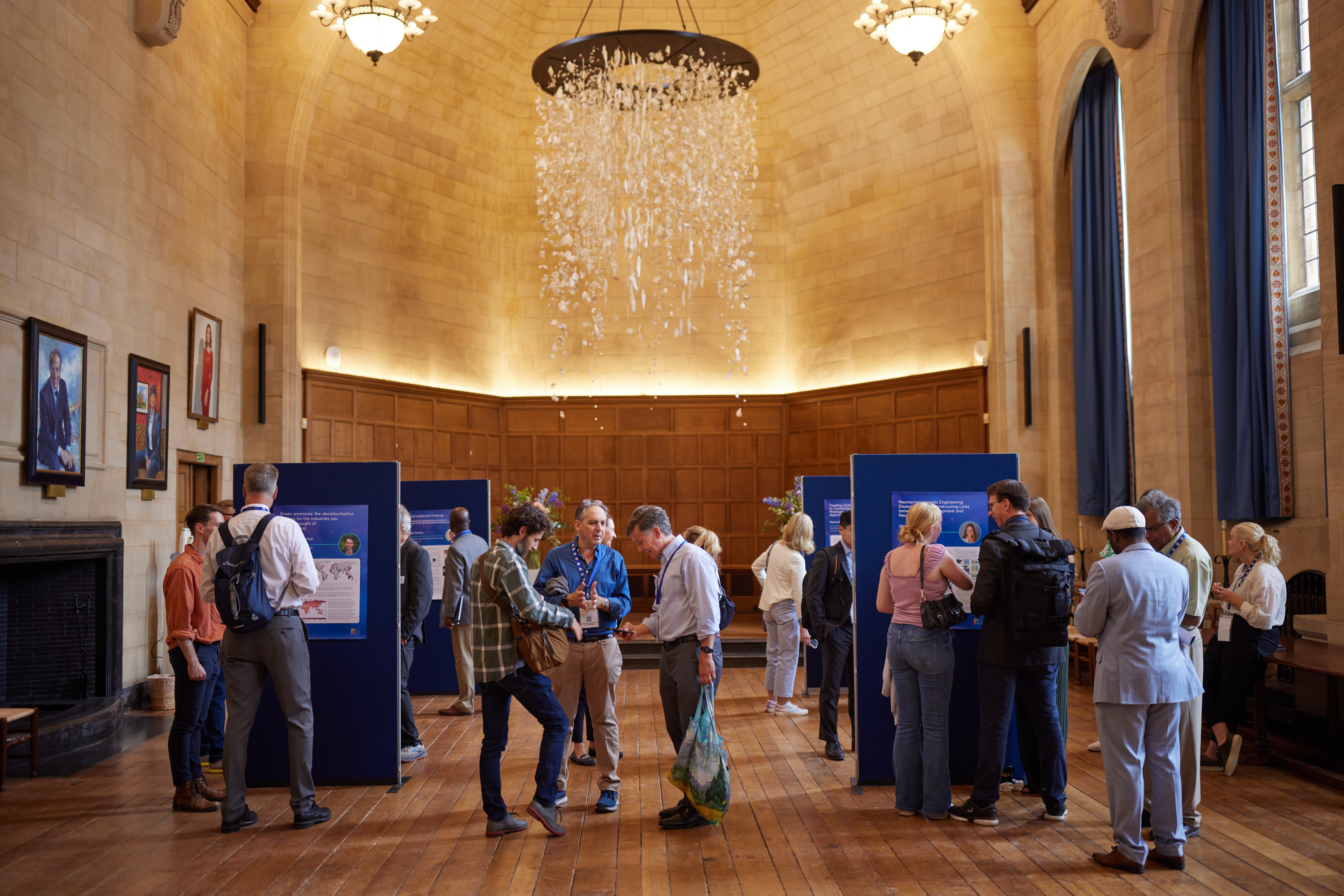 Exhibition boards set up in Rhodes House McCall MacBain Hall with delegates mingling and viewing. 