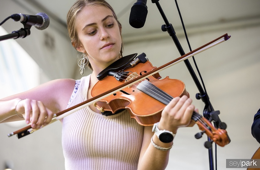 Madeline playing the fiddle next to a microphone