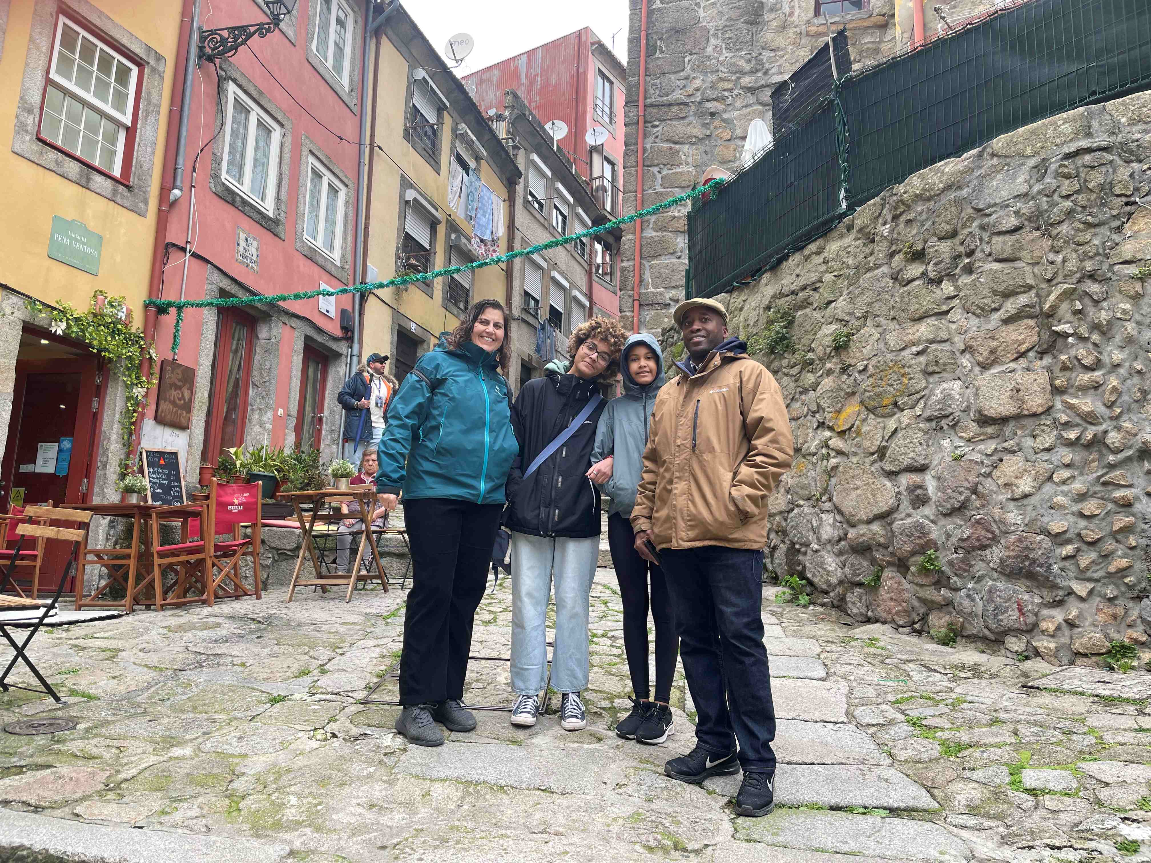 Carol, her husband, and two children stood in the colorful and cobbled streets of Porto looking down at a camera.