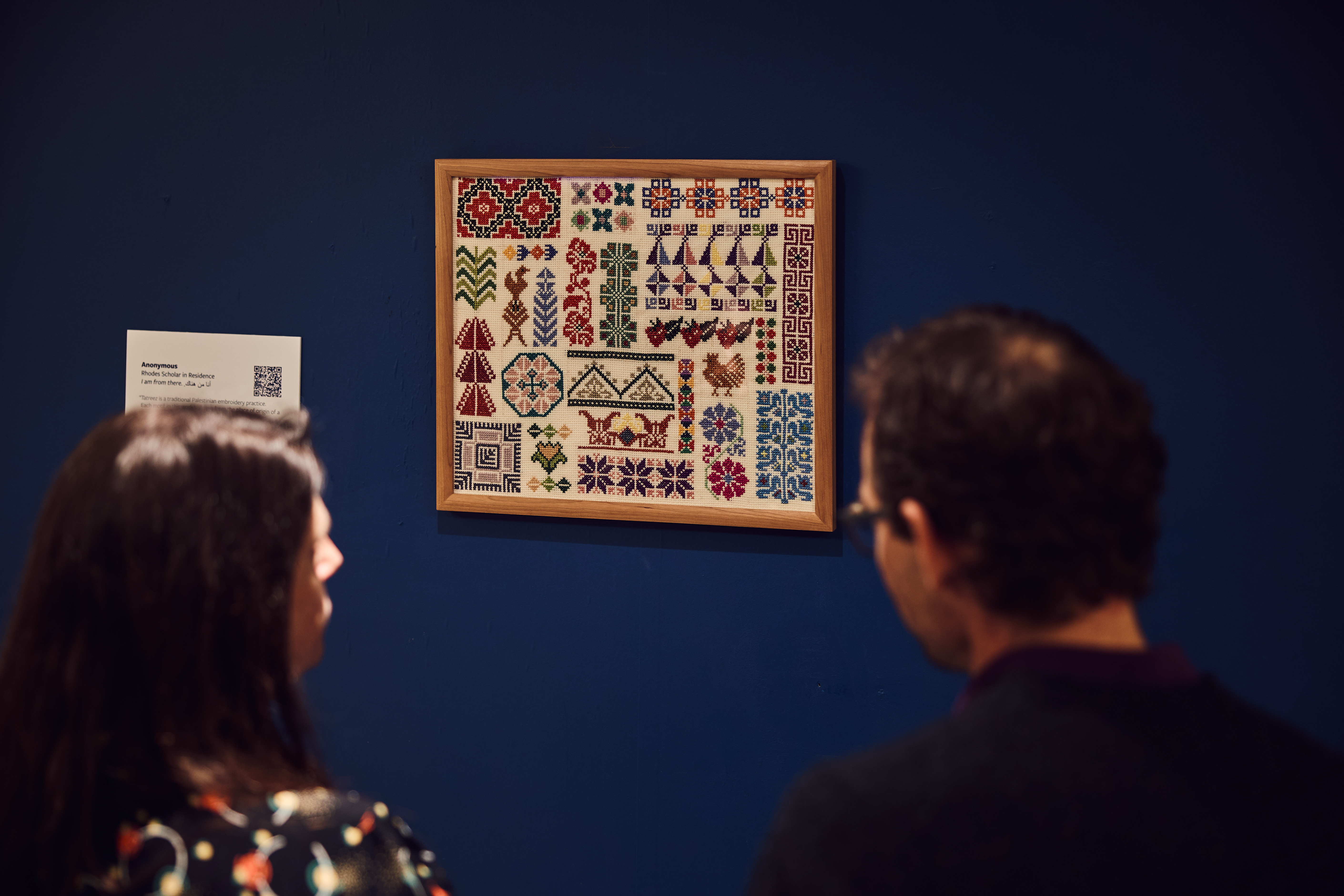 Two people looking at an embroidery artwork
