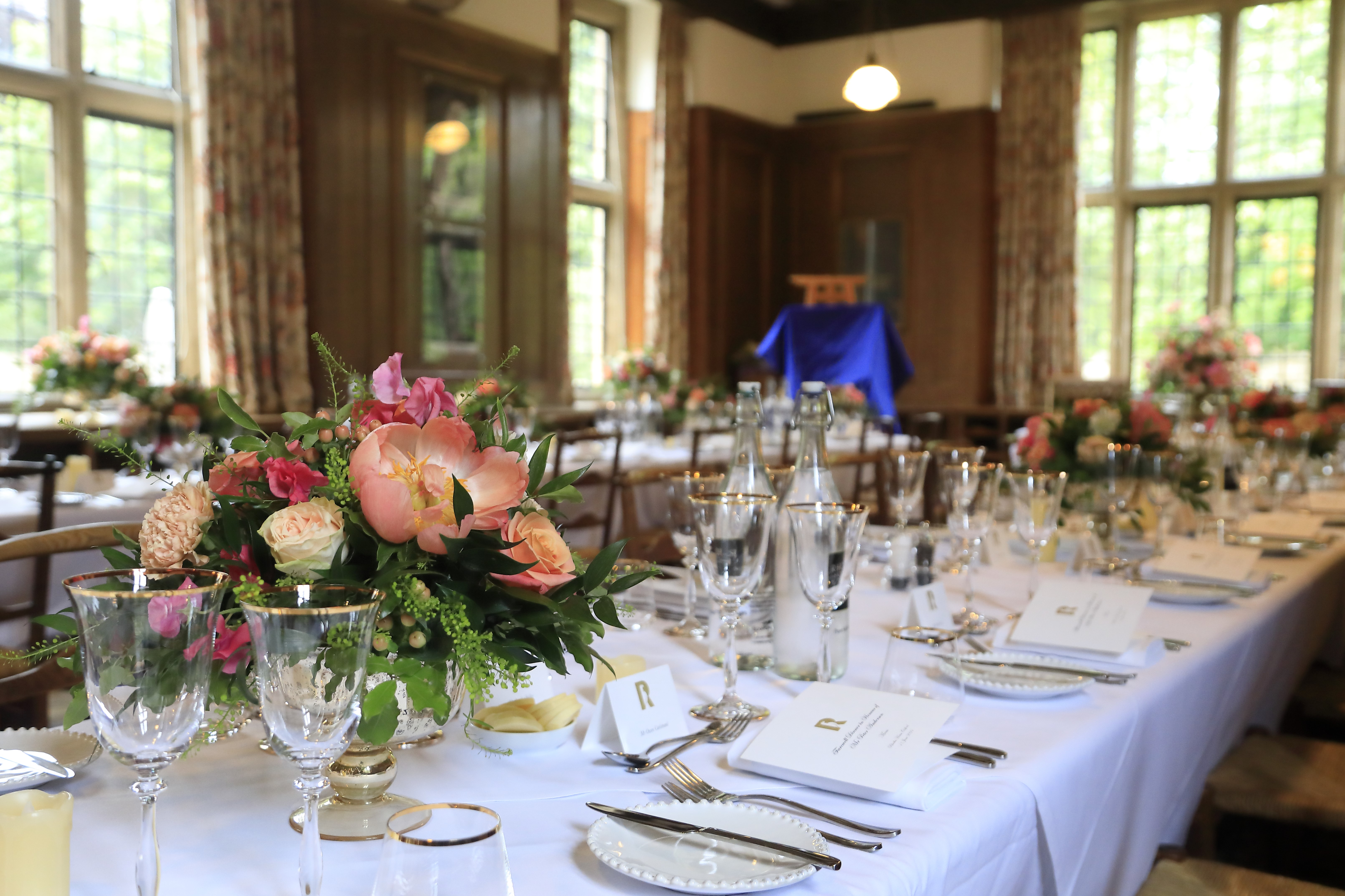 Rhodes House Beit Room dining tables with white cloths and pink flower arrangements.