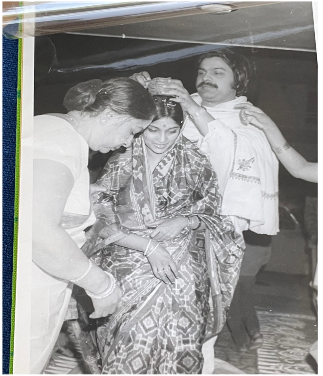 A black-and-white picture showing Jahar and Sunita's wedding, 1972, Delhi.  Sunita is being anointed with red “sindoor powder” in hair-parting in a traditional custom.