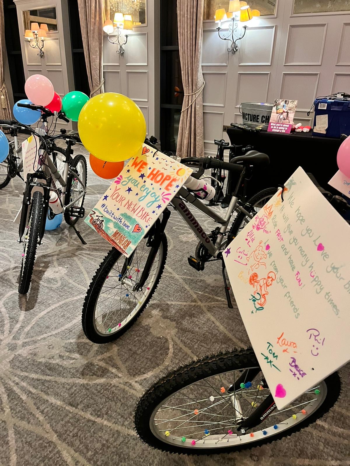 Bicycles created during a charity team building activity, with festive signs and balloons attached.