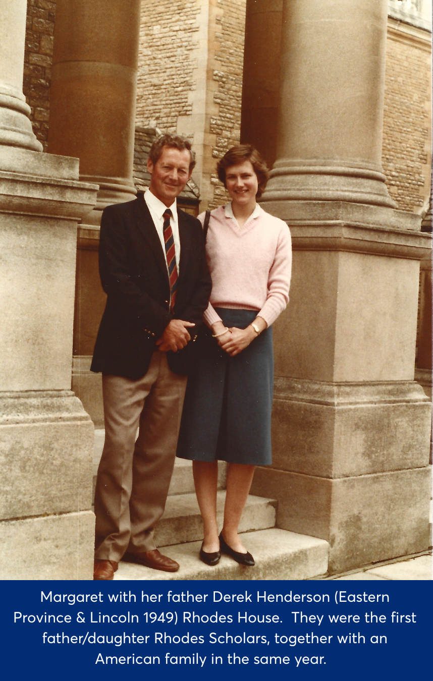 Margie in a pink jumper and blue skirt stood to the right of her father in beige trouser and black blazer. They are stood at the front of Rhodes House before columns.