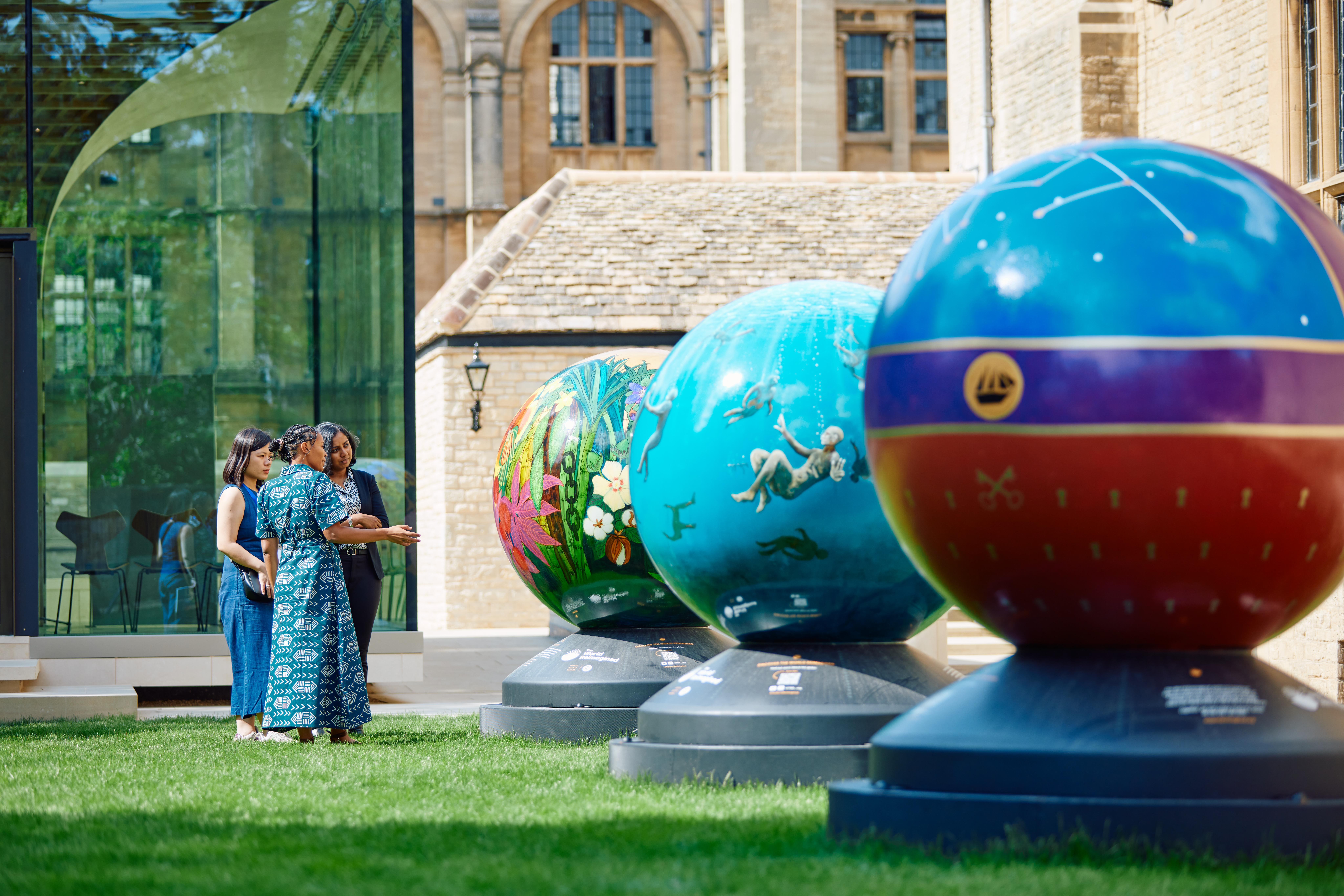 3 women admiring the brightly coloured globes in Rhodes House garden