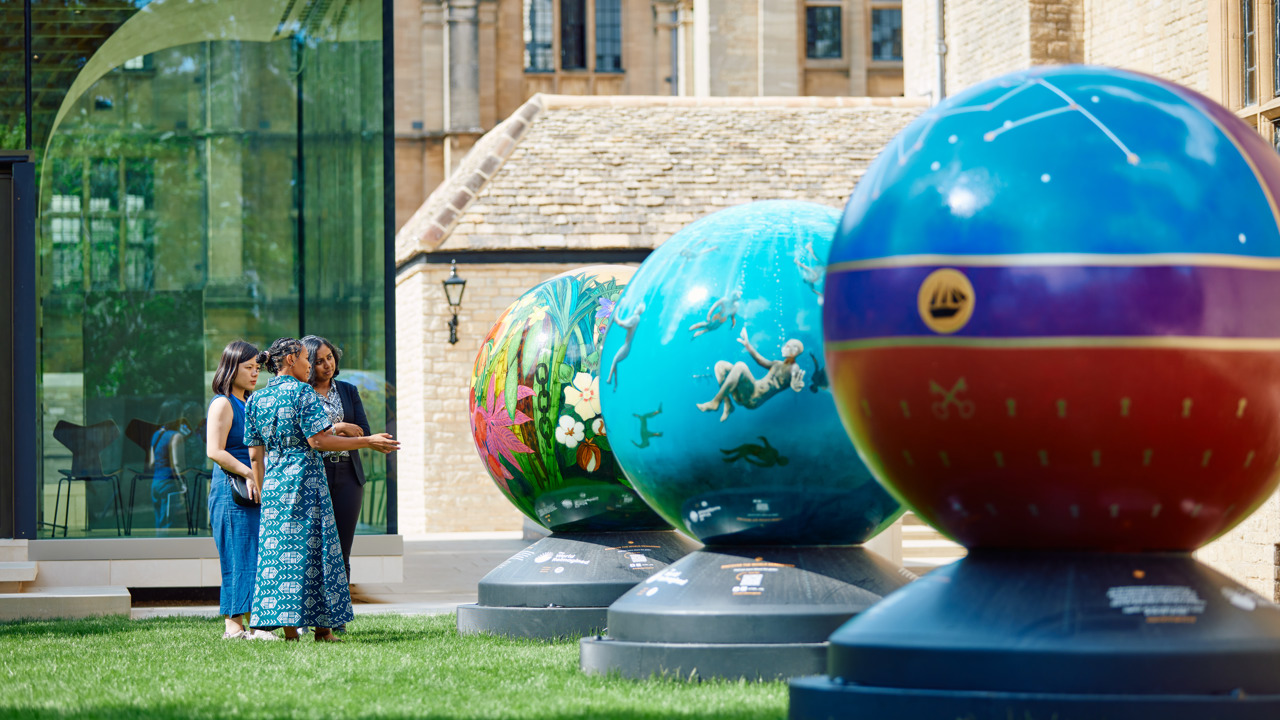 3 women admiring the brightly coloured globes in Rhodes House garden